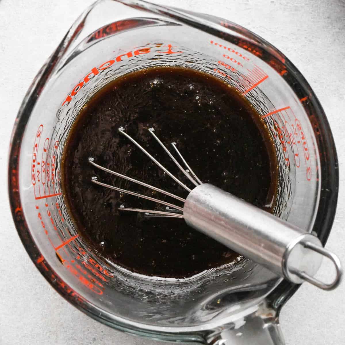 ground beef stir fry sauce in a glass pyrex measuring up with a metal whisk