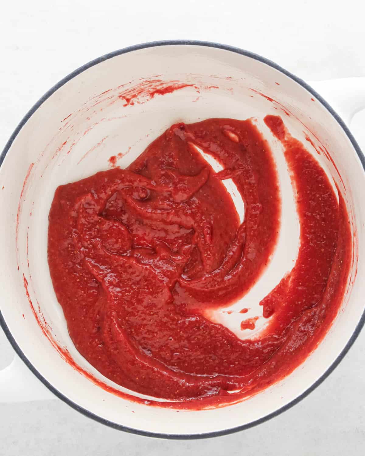 making strawberry cake - thickened strawberry reduction in a white saucepan