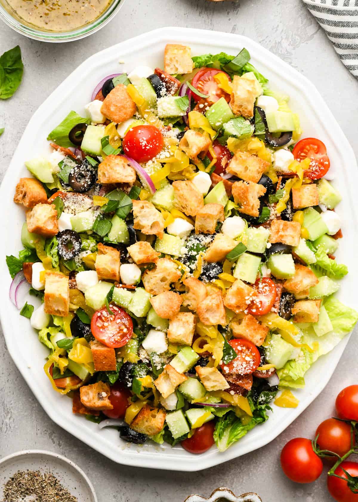 assembled Italian salad topped with croutons on a white serving plate