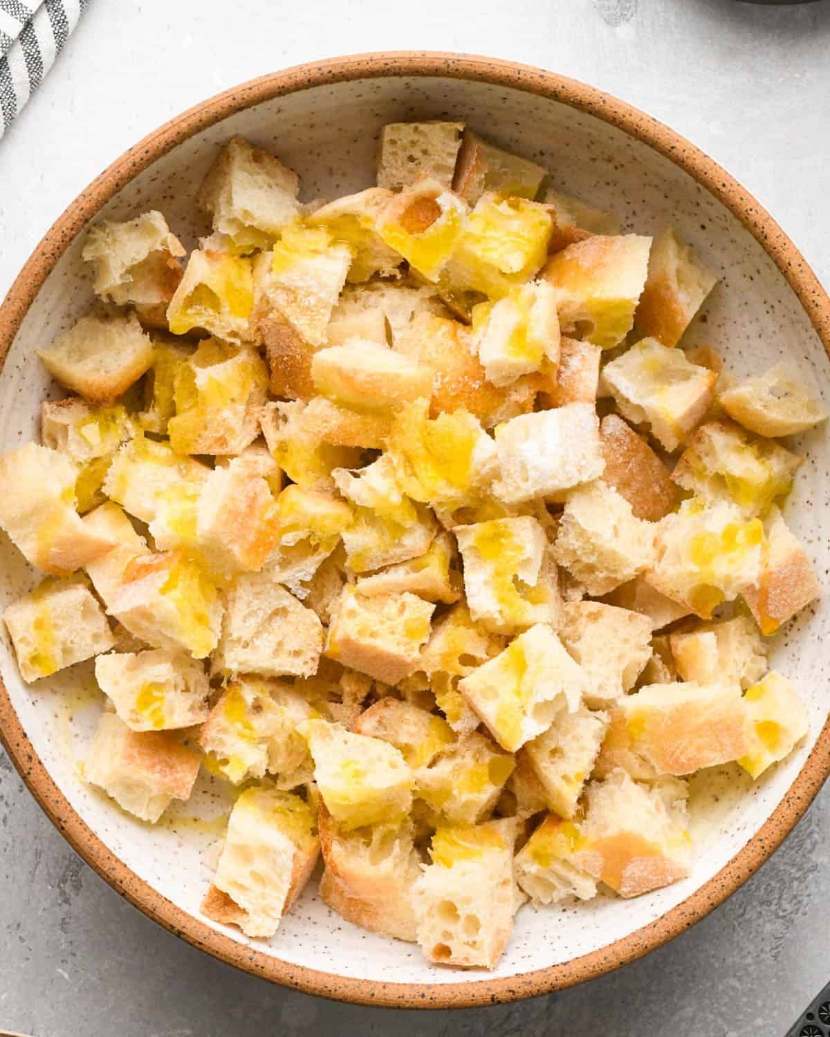 making croutons for Italian salad - bread cubes drizzled with olive oil in a bowl