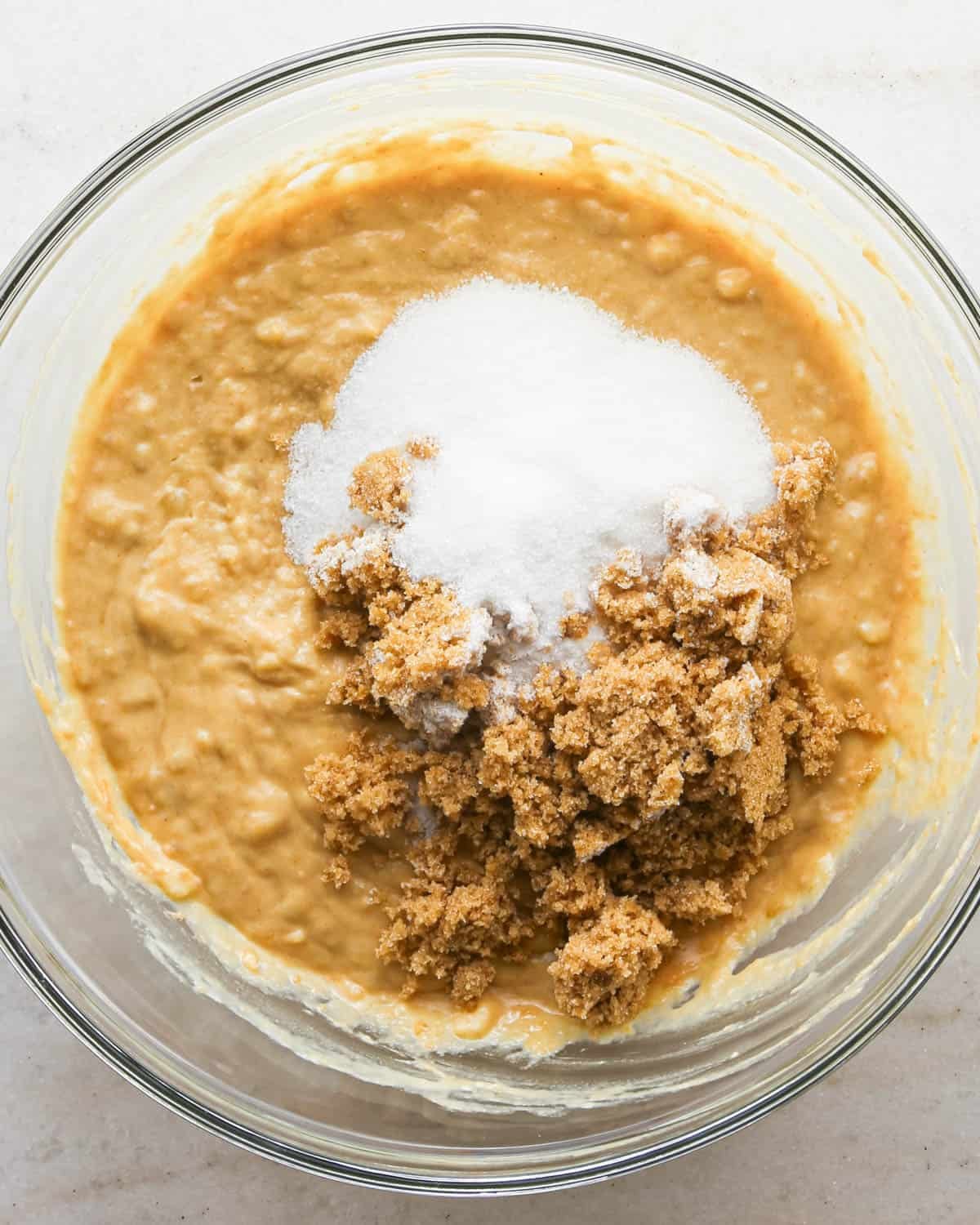 making peanut butter banana muffins - white sugar and brown sugar added to the wet ingredient mixture before stirring in a glass bowl