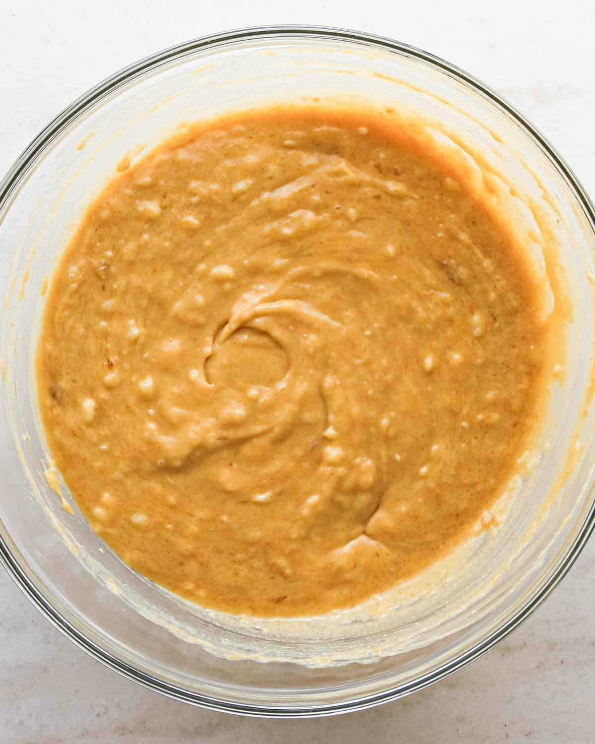 making peanut butter banana muffins - wet ingredients and sugars mixed together in a glass bowl