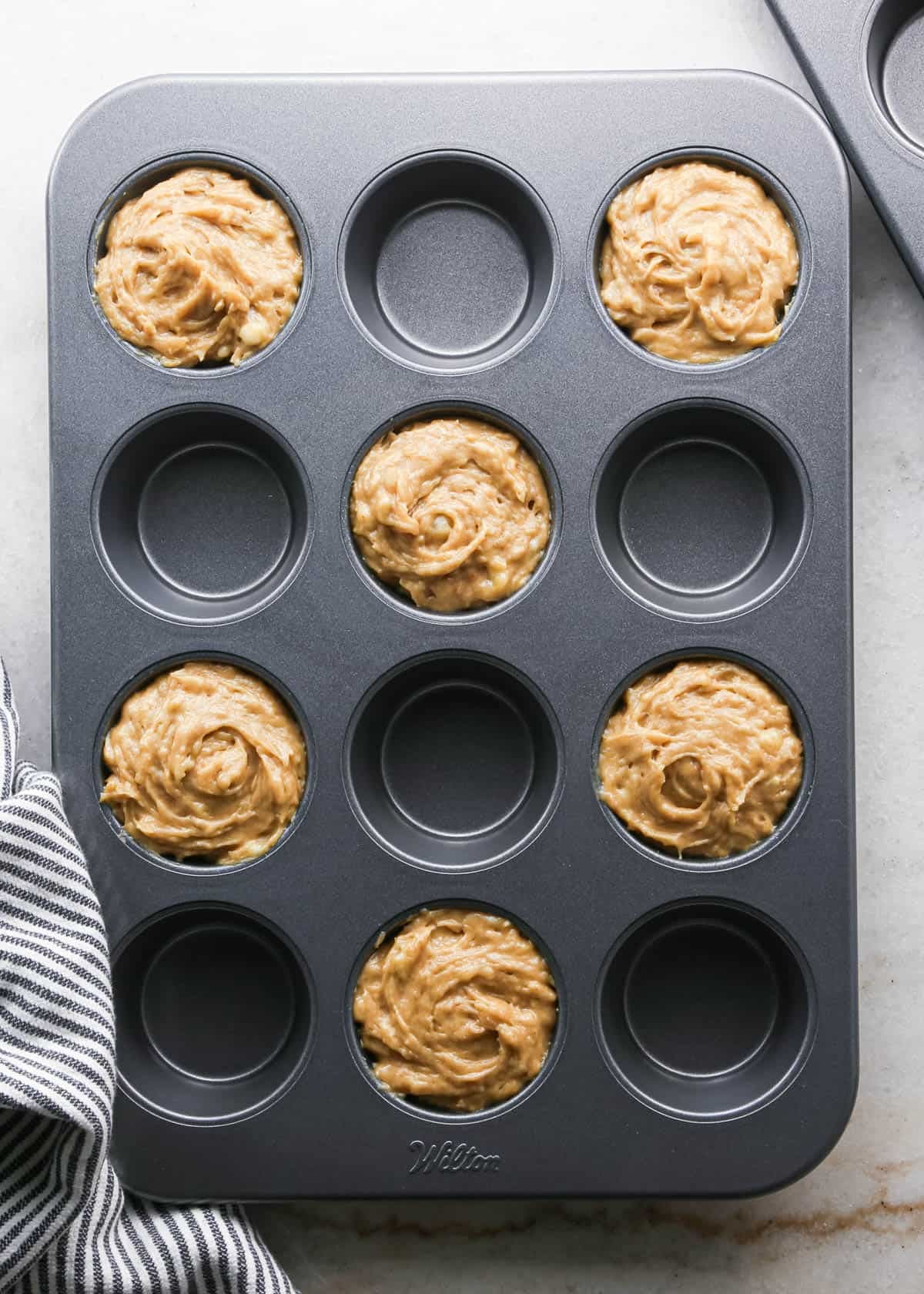 making peanut butter banana muffins - 6 wells of a muffin tin filled with batter before baking