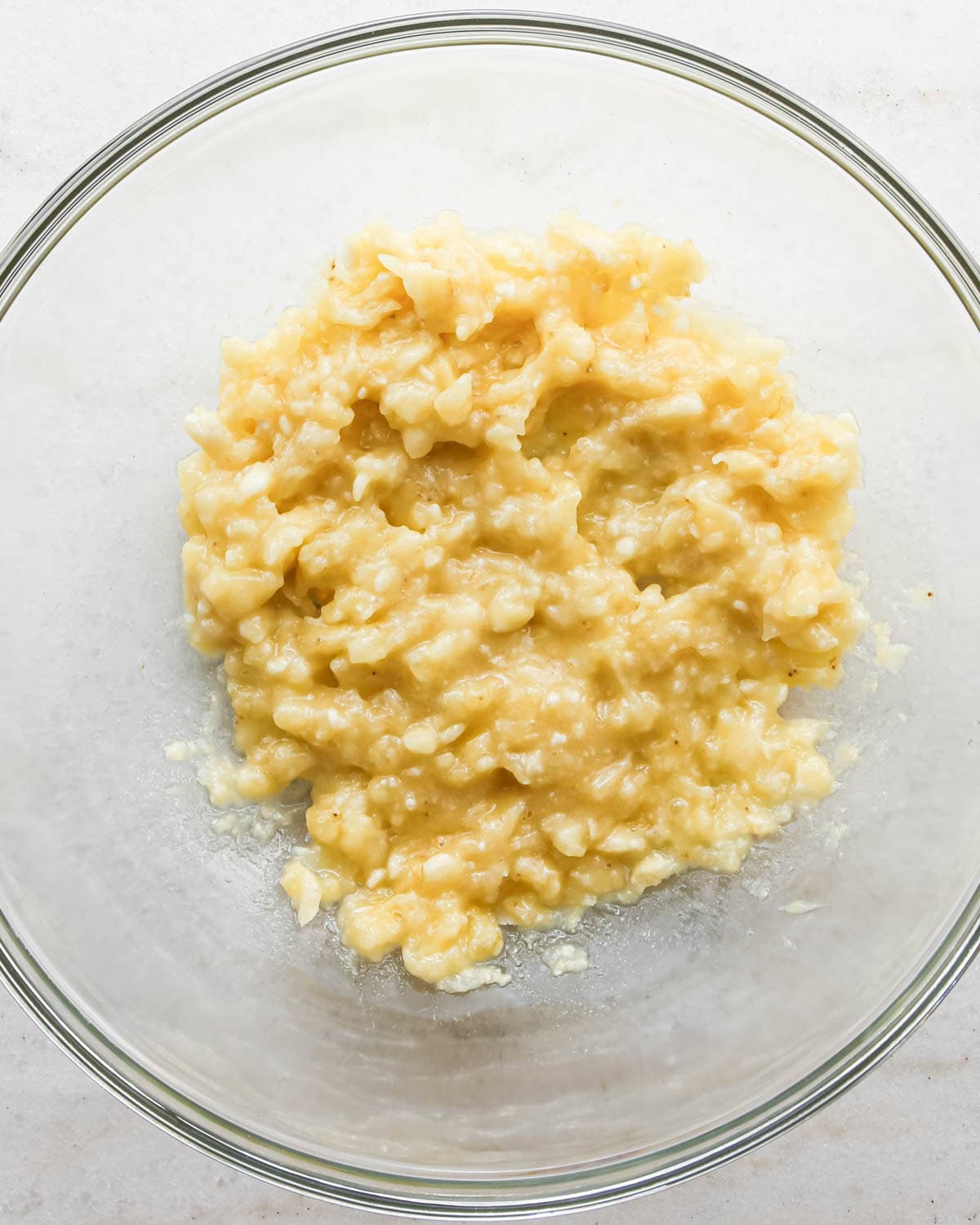 making peanut butter banana muffins - mashed bananas in a glass bowl