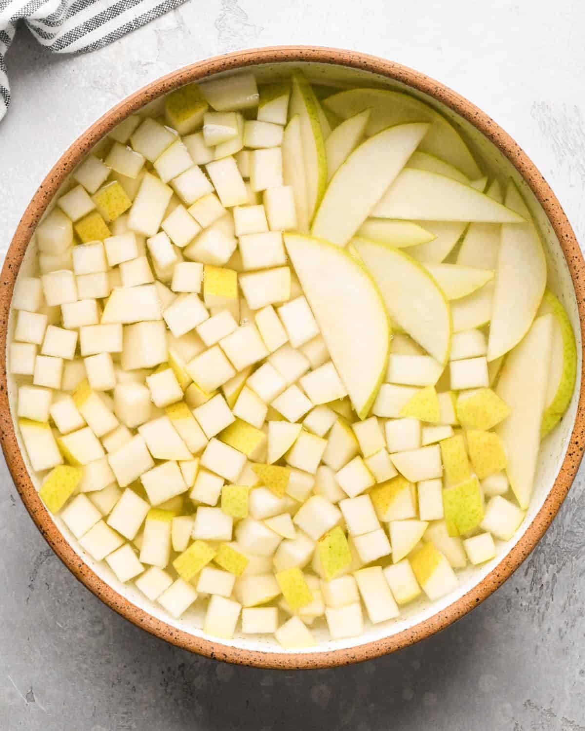 how to make pear salad - diced and sliced pears soaking in a bowl of lemon juice and water