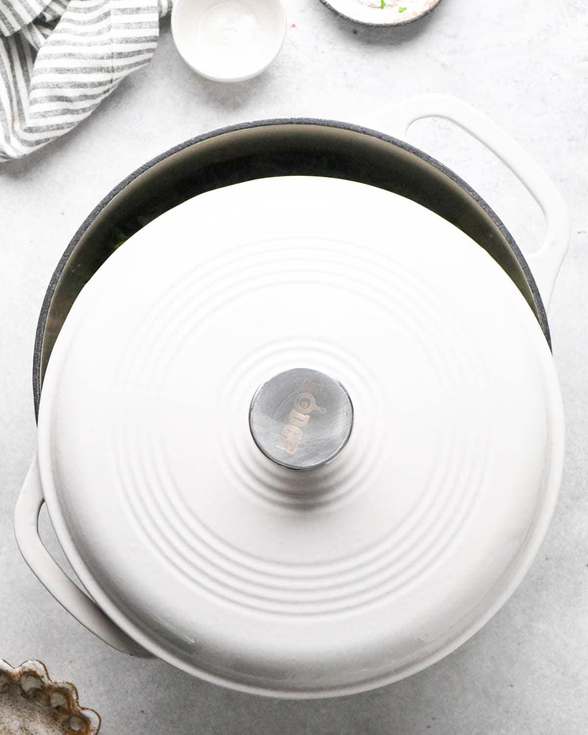 making sausage kale and white bean soup - a white dutch oven with the lid slightly ajar