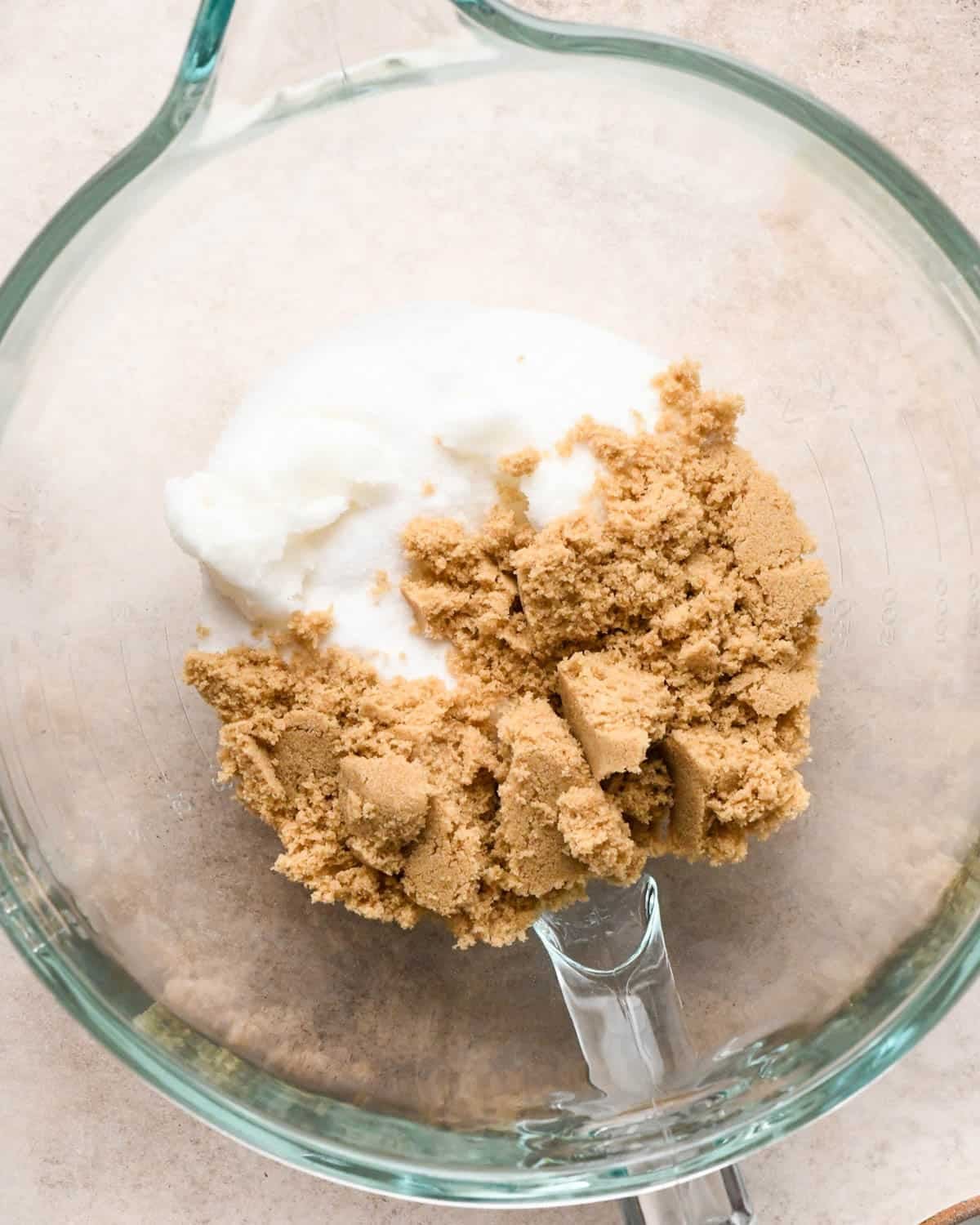 making vegan oatmeal cookies - coconut oil, white sugar and brown sugar in a glass mixing bowl before mixing