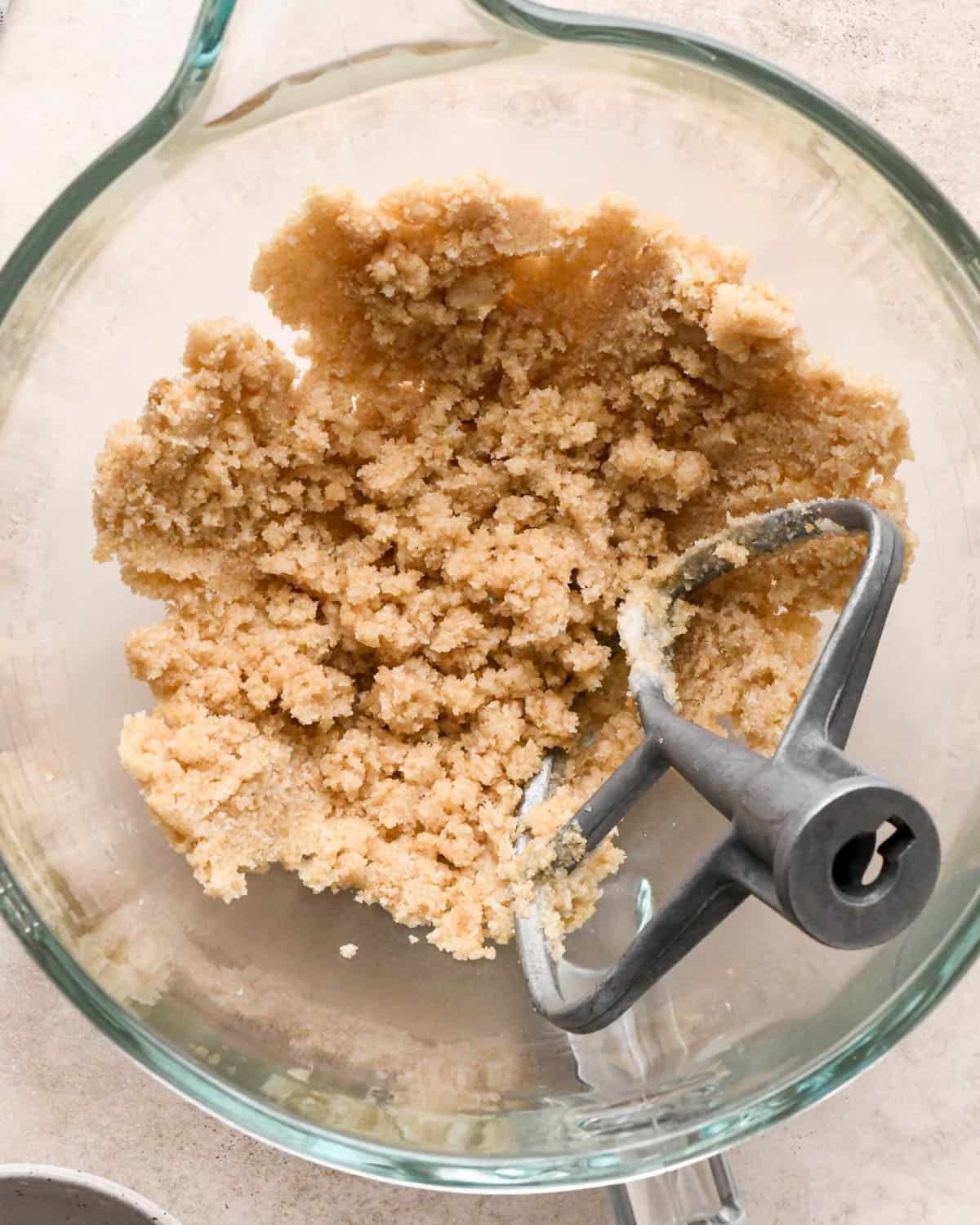 making vegan oatmeal cookies - coconut oil, white sugar and brown sugar in a glass mixing bowl after mixing with the paddle attachment also in the bowl