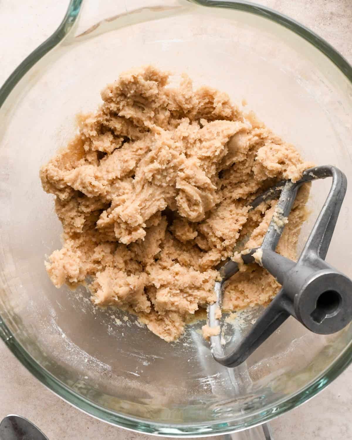 making vegan oatmeal cookies - dough in a glass mixing bowl with the paddle attachment