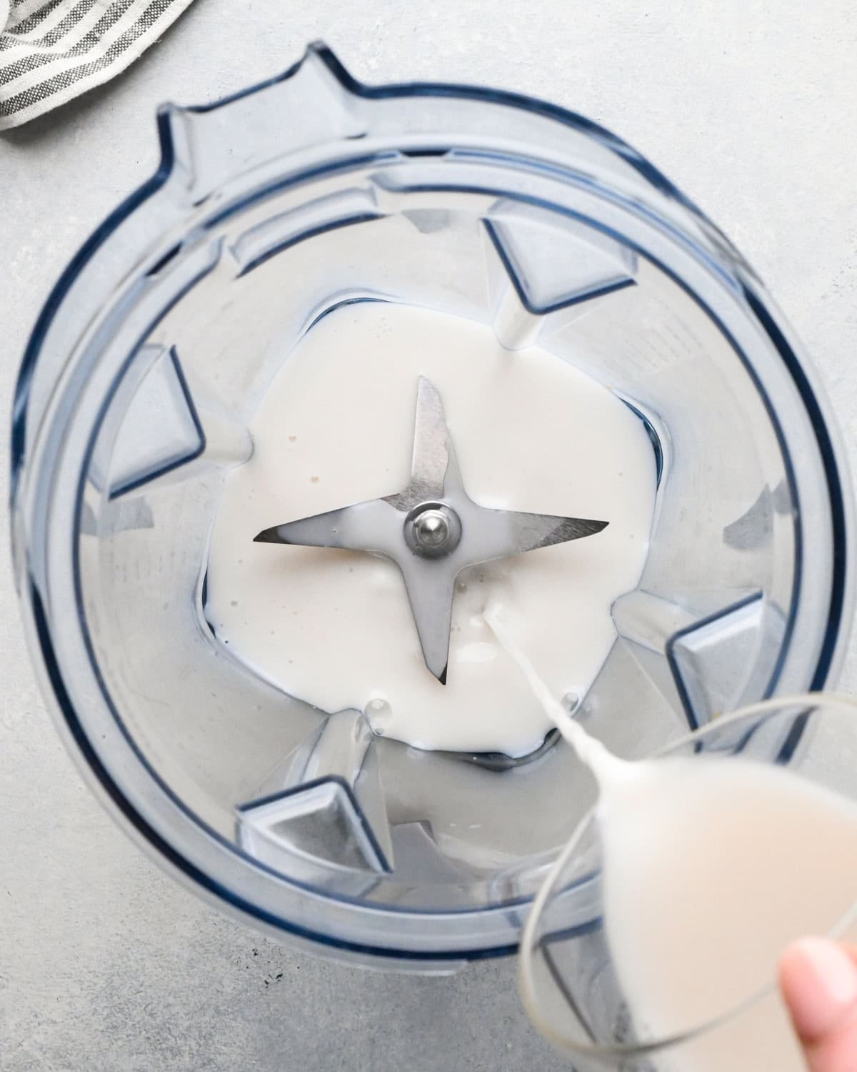 Making carrot fruit smoothie: overhead view of milk being poured into a blender.