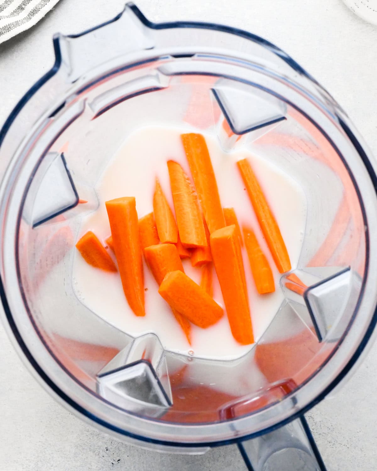 Making carrot fruit smoothie: overhead view of milk and carrots sitting in a blender.