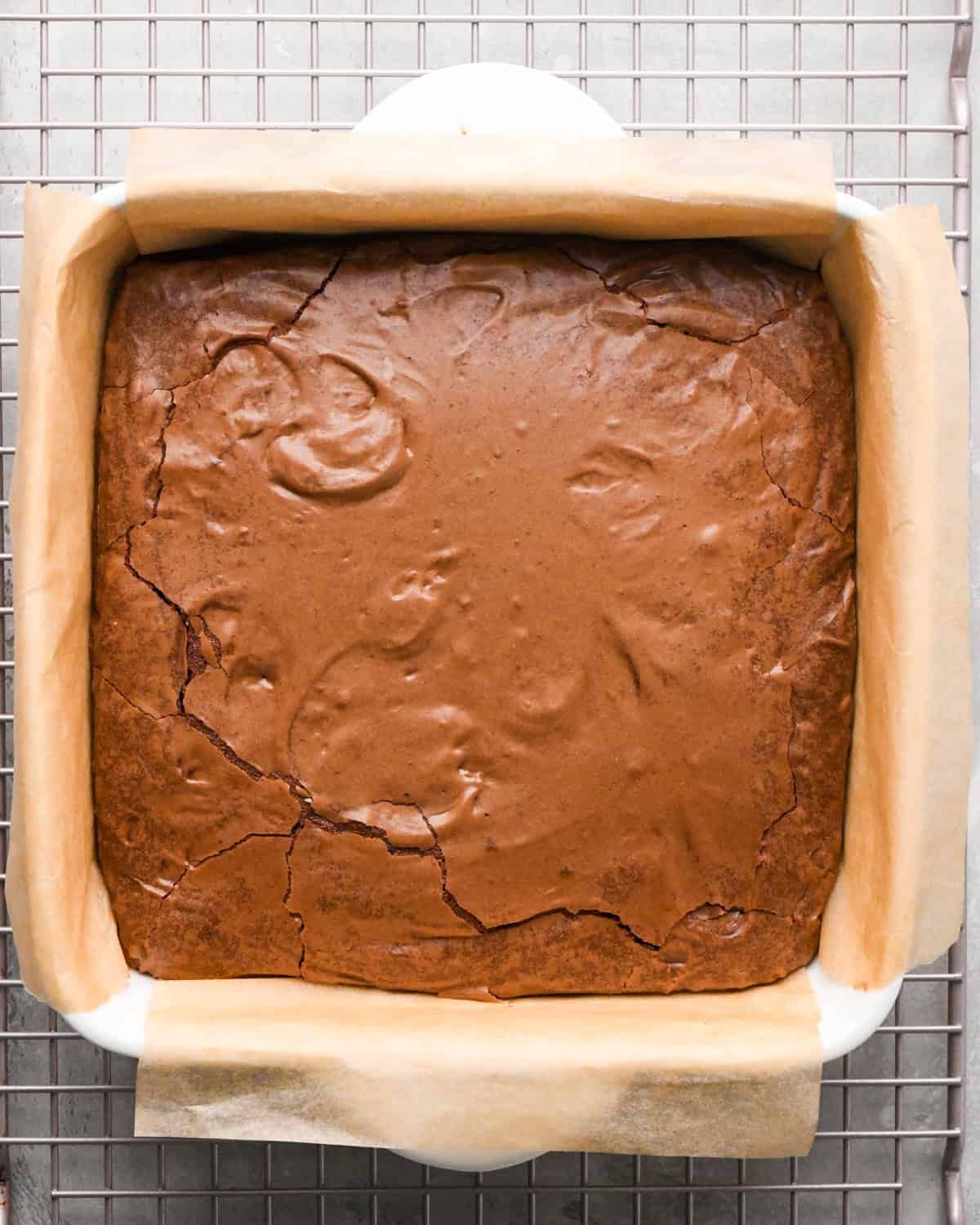 Making gluten-free brownies: overhead photo of completed brownies in a square casserole dish after baking. The brownies are sitting on top of a metal cooling sheet.