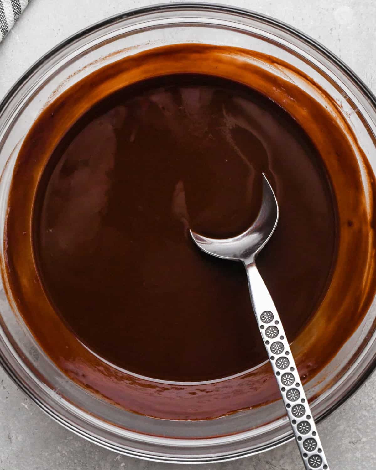 Making gluten-free brownies: overhead photo of butter and chocolate chips added to a large clear bowl, melted together, and being stirred with a wooden spoon.