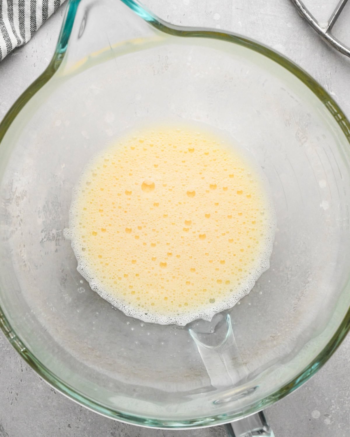 Making gluten-free brownies: overhead photo of 2 eggs cracked into a clear glass measuring bowl and beaten together.
