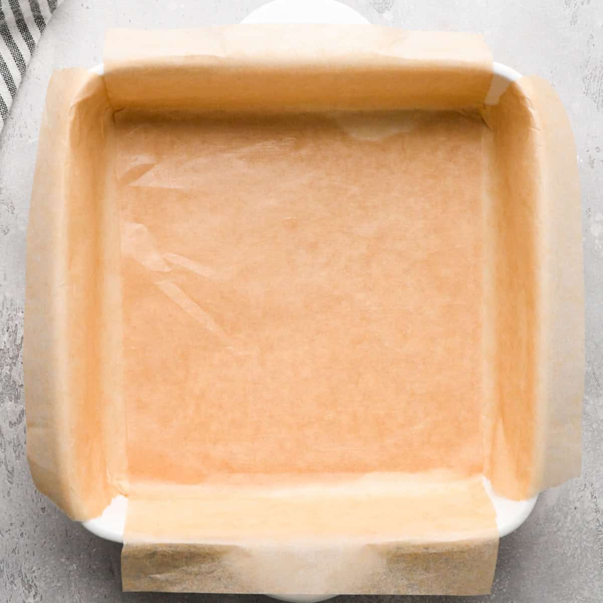 Making gluten-free brownies: overhead photo of a parchment paper-lined white casserole dish.