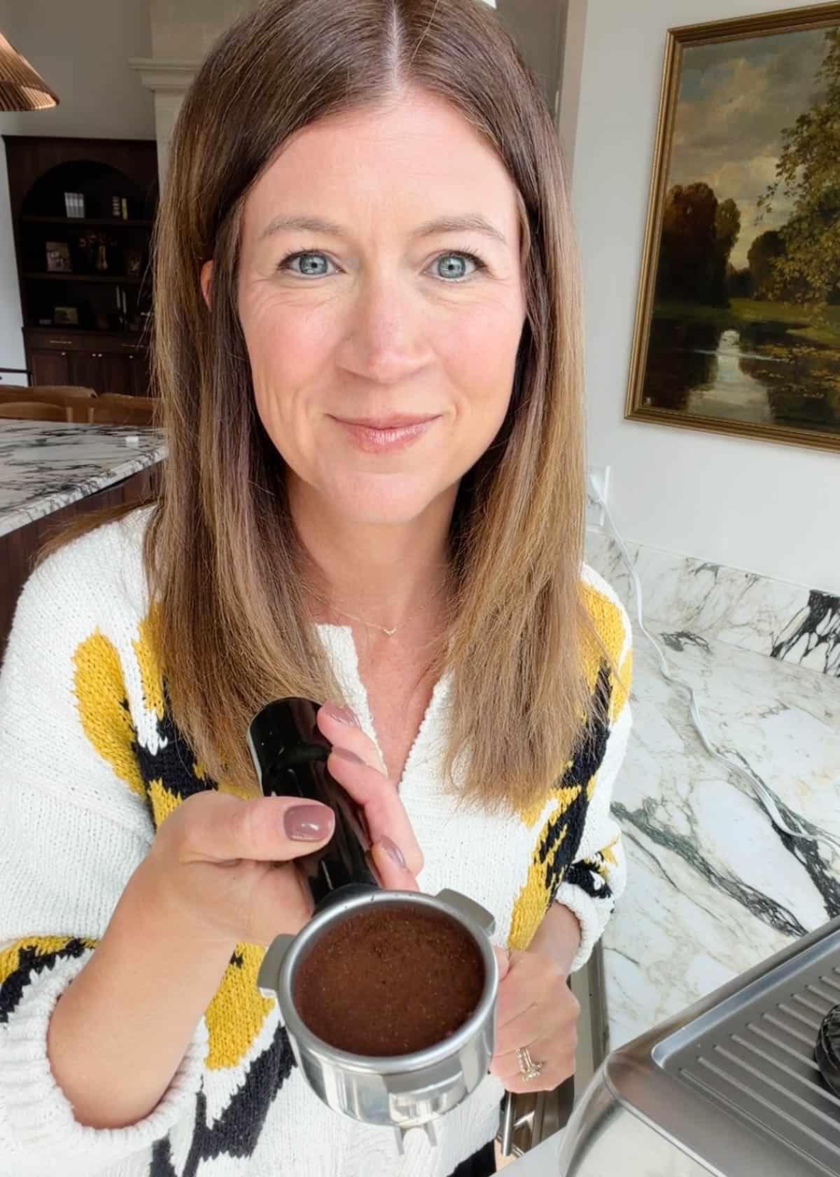 how to make a latte - woman holding beans ground and tamped in a portafilter