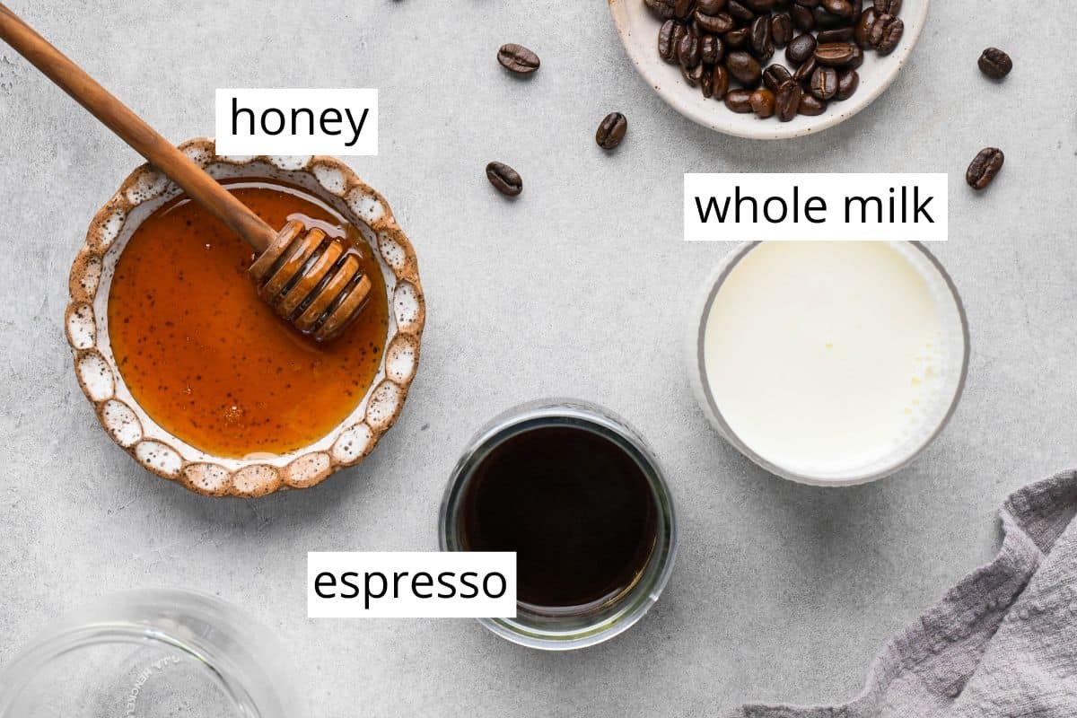 Overhead photo of the ingredients for a homemade latte, including espresso, honey, and whole milk.