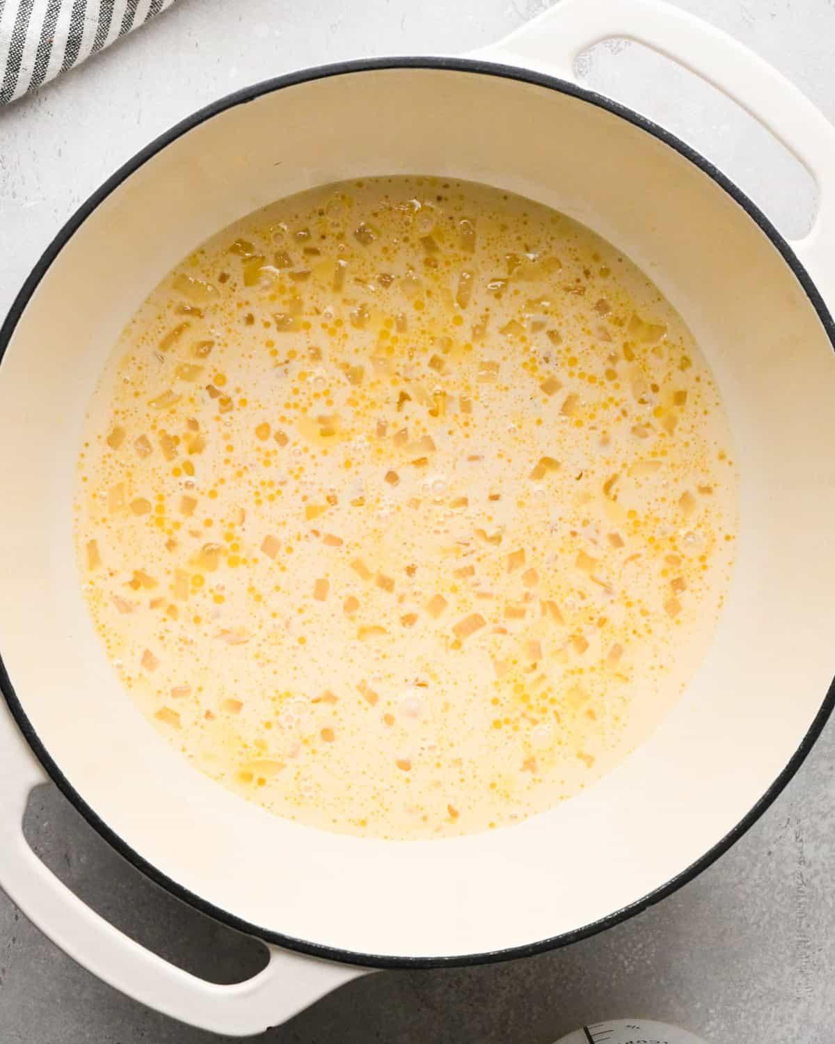 Making homemade queso: overhead photo of ingredients for homemade queso simmering together in a large white pot.