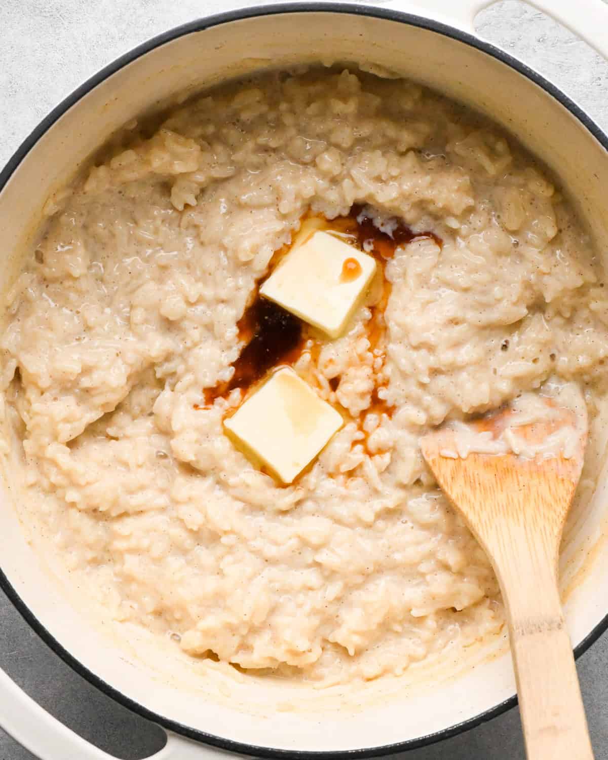 Making rice pudding: overhead photo of butter and vanilla added to a large pot with the rice pudding.