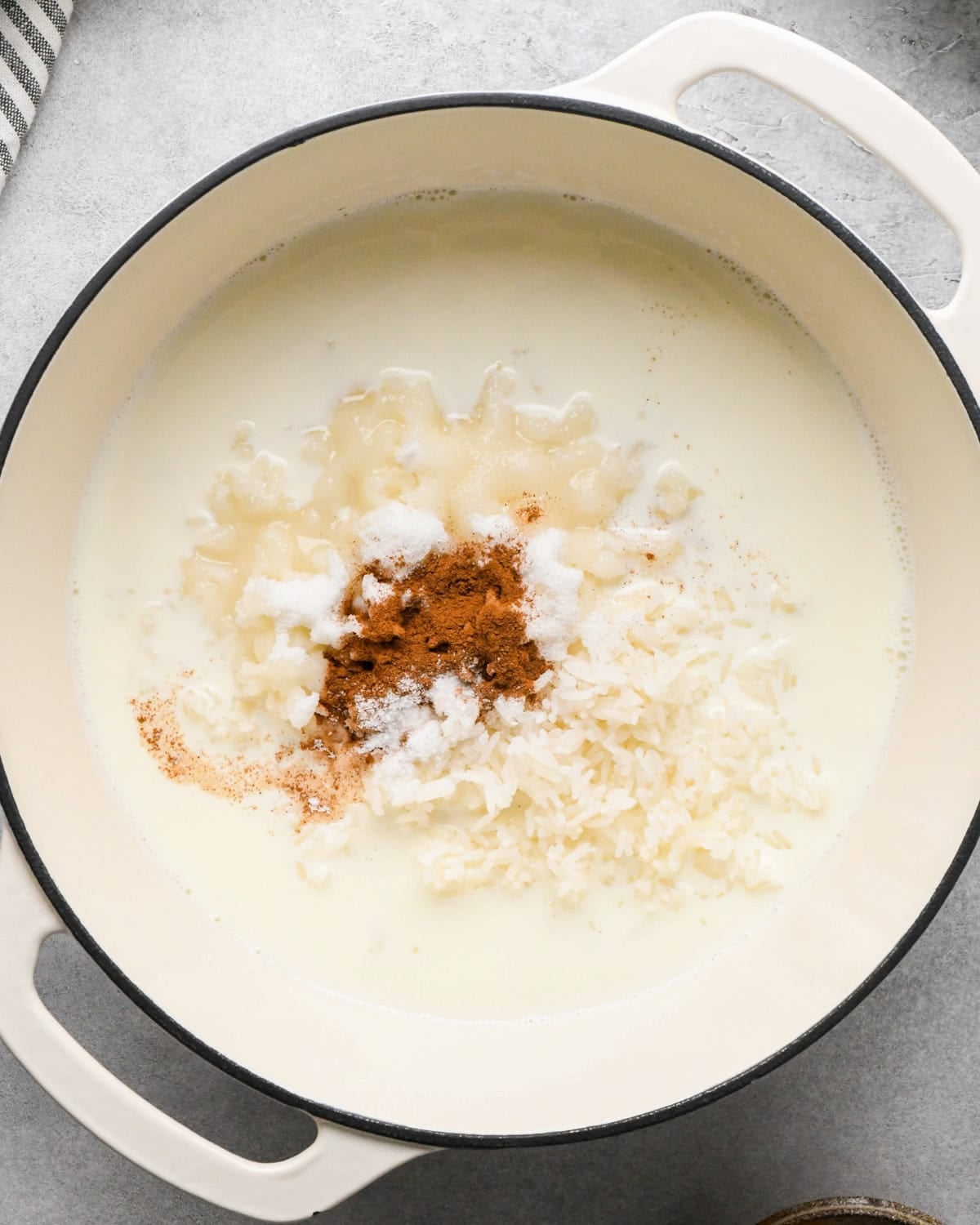 Making rice pudding: overhead photo of wet and dry ingredients for rice pudding added to a large white pot.