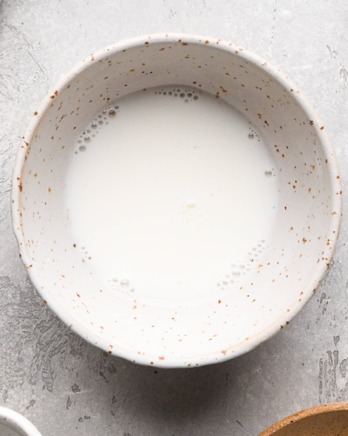 Making homemade strawberry sauce: overhead photo of water and cornstarch in a white speckled bowl and mixed together.