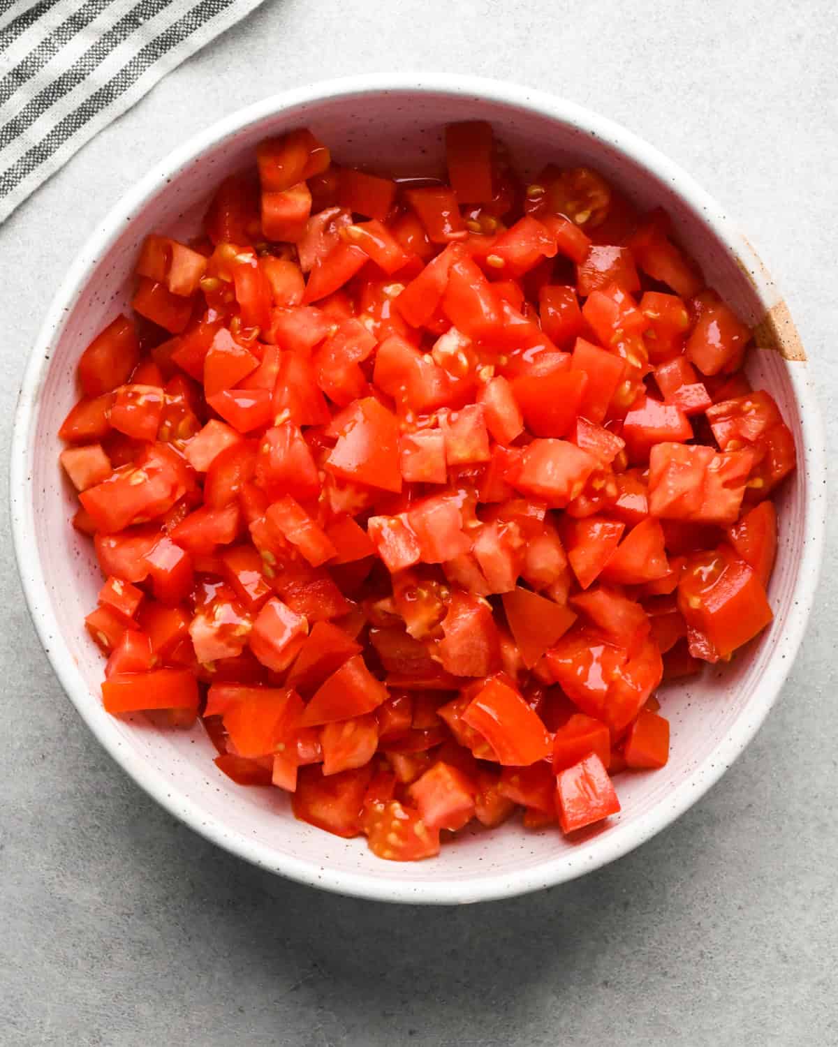 Making pico de Gallo: overhead photo of a white bowl filled with diced tomatoes.
