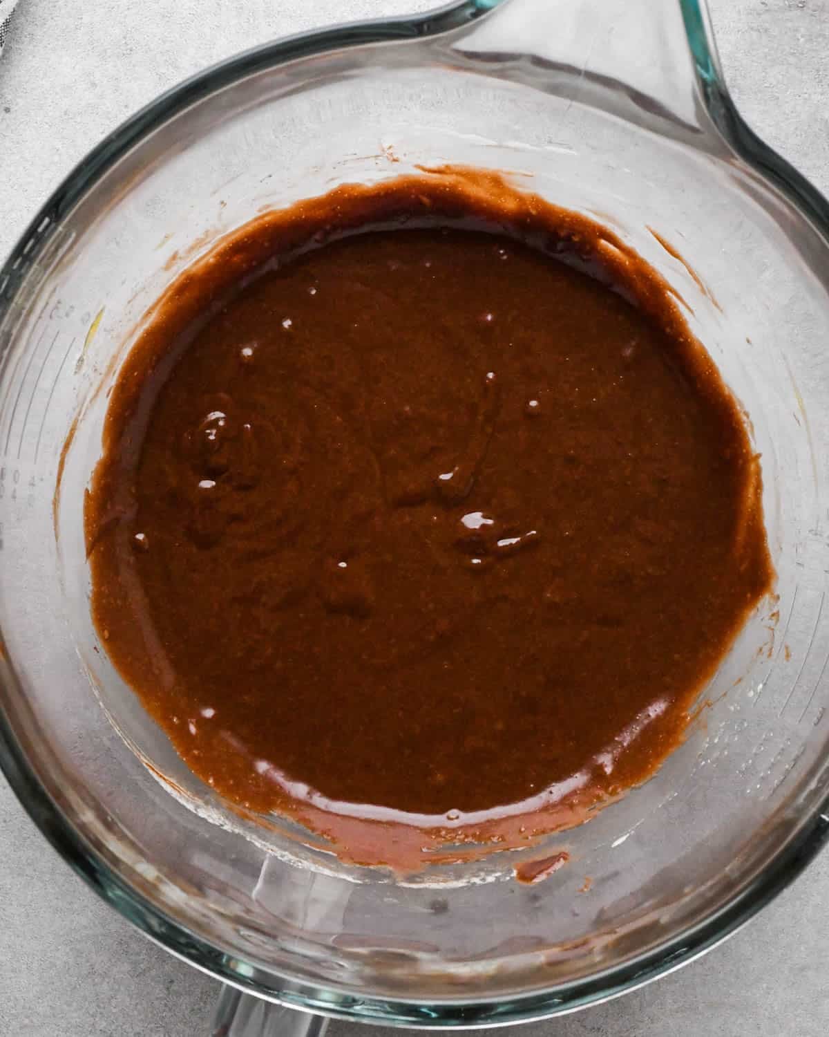 Making buckeye brownies: overhead photo of melted chocolate/butter and vanilla mixed together with the beaten sugar and eggs in a glass measuring bowl.