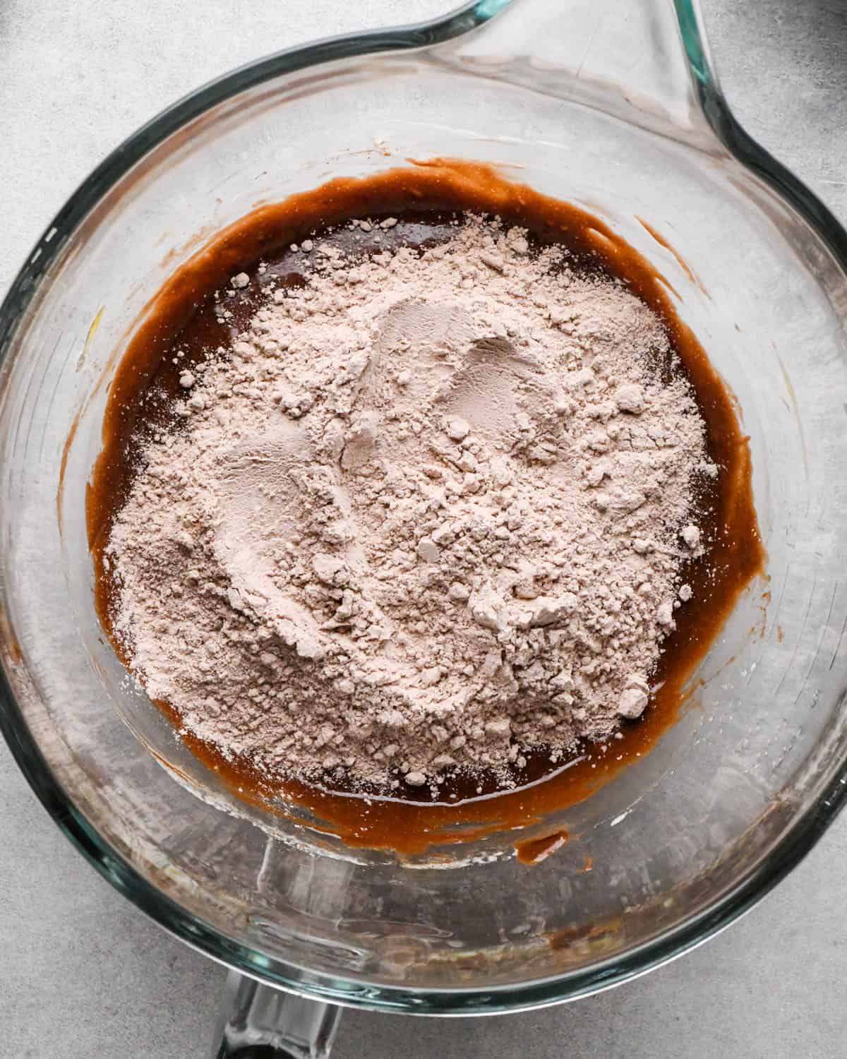 Making buckeye brownies: overhead photo of dry ingredient mixture being poured into the measuring bowl with the wet ingredients.