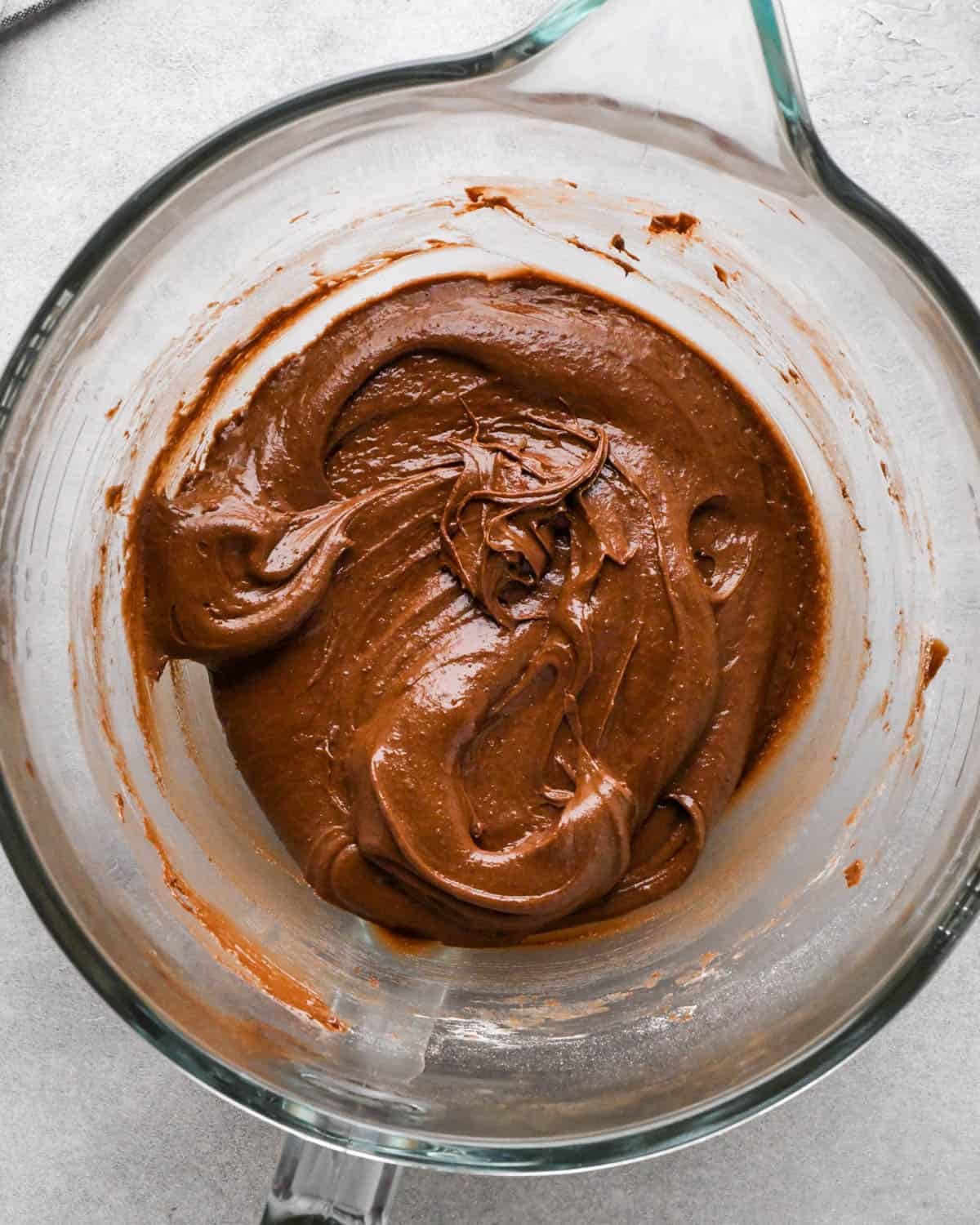 Making buckeye brownies: overhead photo of dry ingredient mixture being poured into the measuring bowl with the wet ingredients and mixed together.