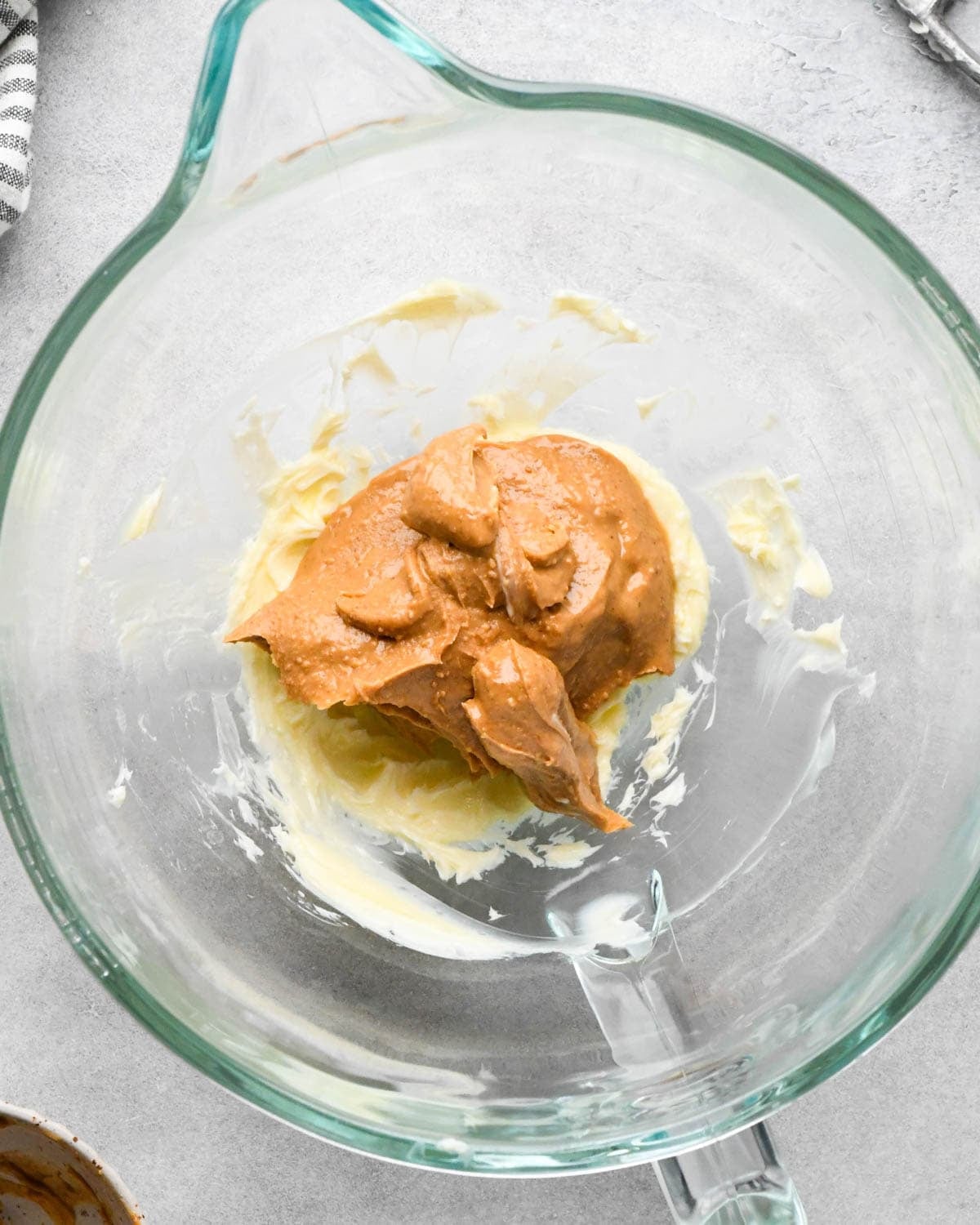 Making buckeye brownies: overhead photo of peanut butter added to the beaten butter in a glass measuring bowl.