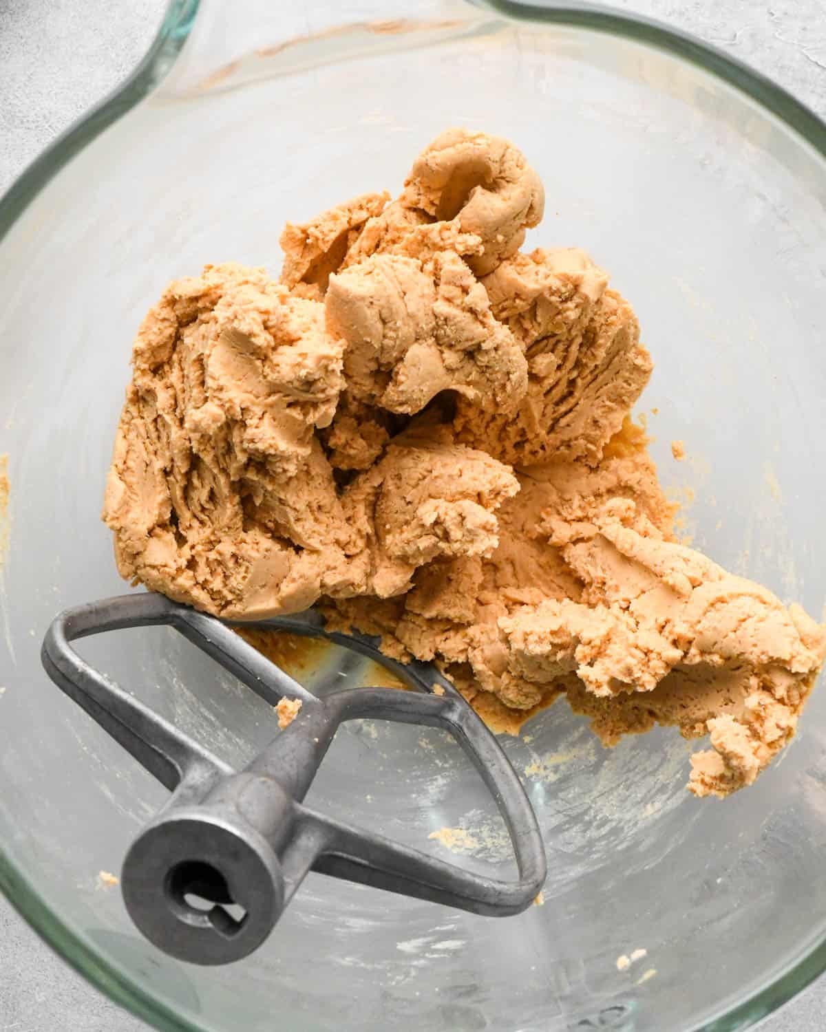 Making buckeye brownies: overhead photo of whole milk mixed into the peanut butter mixture in a glass measuring bowl. A paddle attachment is resting in the bowl.