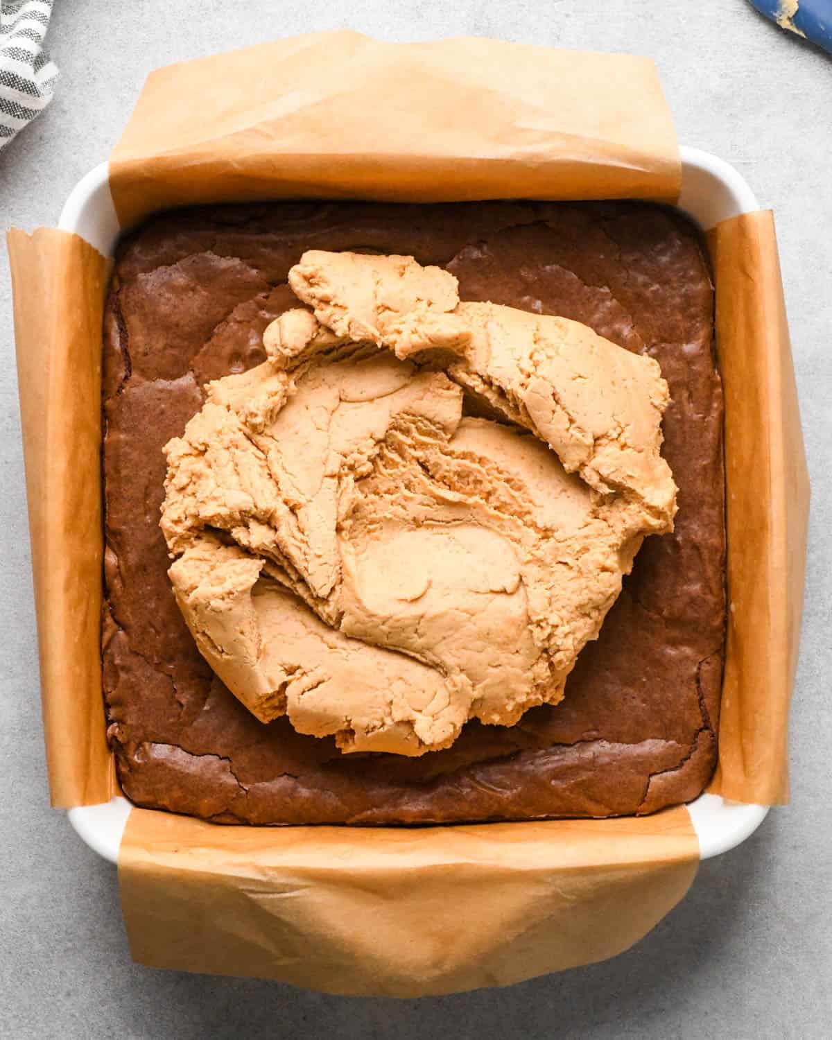 Making buckeye brownies: overhead photo of completed peanut butter mixture poured onto the chilled brownie layer in a 9x9" baking dish.