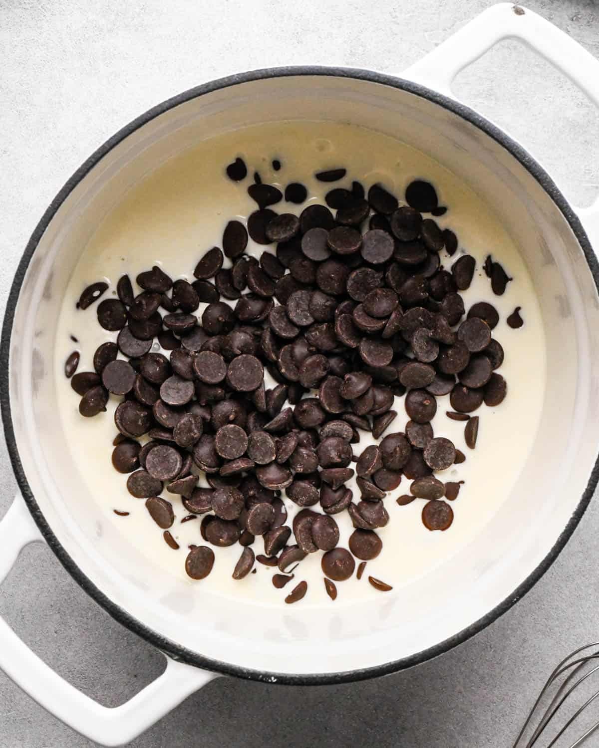 Making chocolate ganache: overhead photo of heavy cream and chocolate in a large white pot.