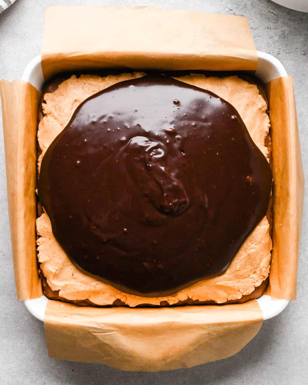 Making buckeye brownies: overhead photo of completed chocolate ganache poured onto the brownies in a 9x9" baking dish.
