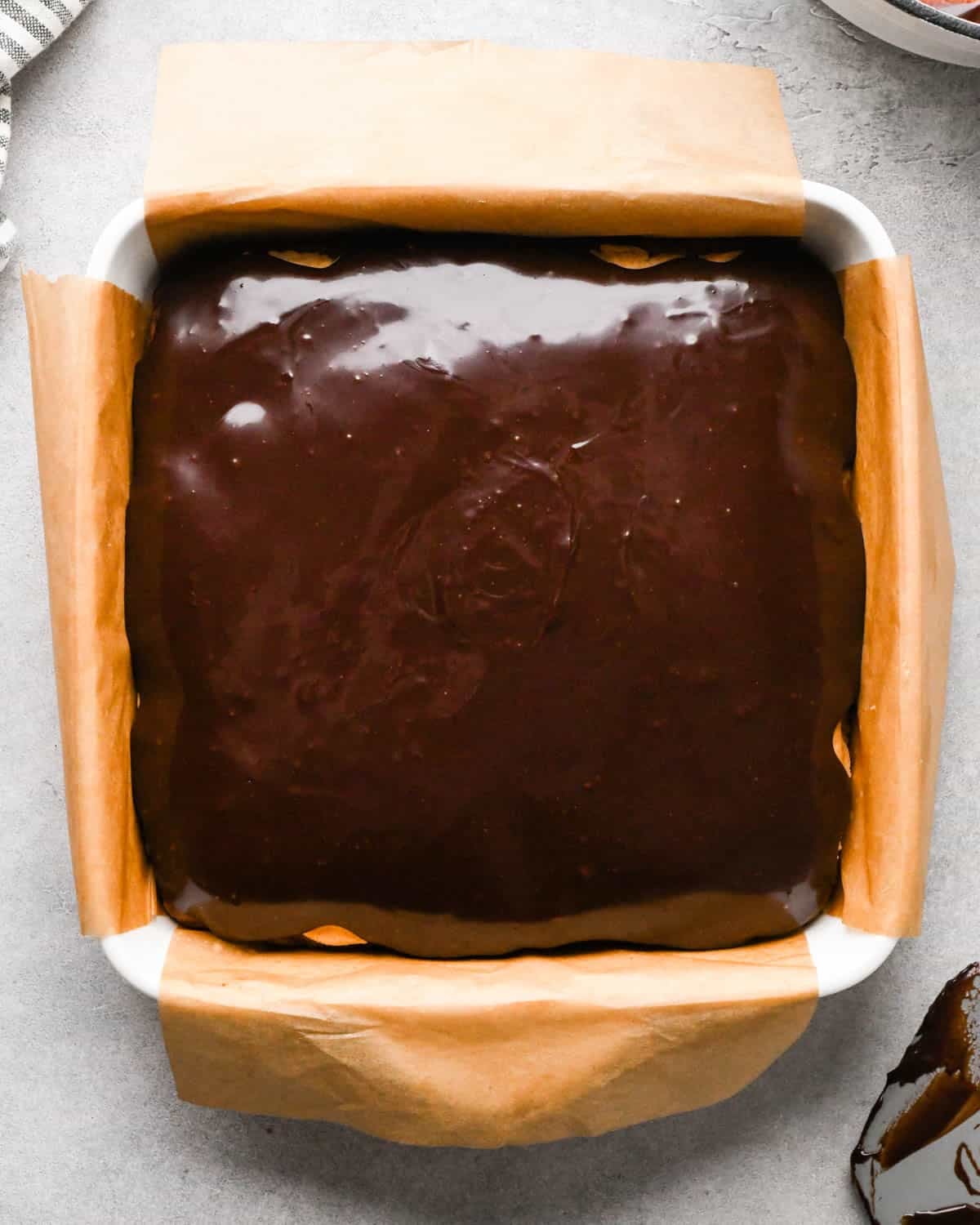 Making buckeye brownies: overhead photo of completed chocolate ganache poured onto and spread over the brownies in a 9x9" baking dish.