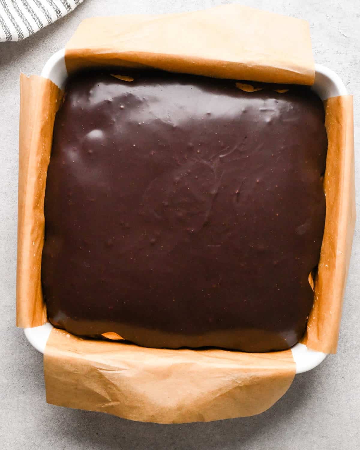 Making buckeye brownies: overhead photo of completed buckeye brownies - with a brownie layer, a peanut butter layer, and a chocolate ganache layer - in a 9x9" baking dish.