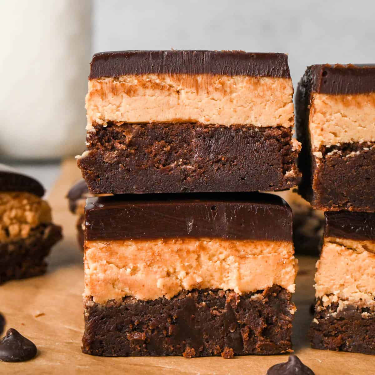 Up-close photo of stacked buckeye brownies with a fudgy chocolate brownie base, creamy peanut butter layer, and smooth chocolate ganache topping on a wooden surface.