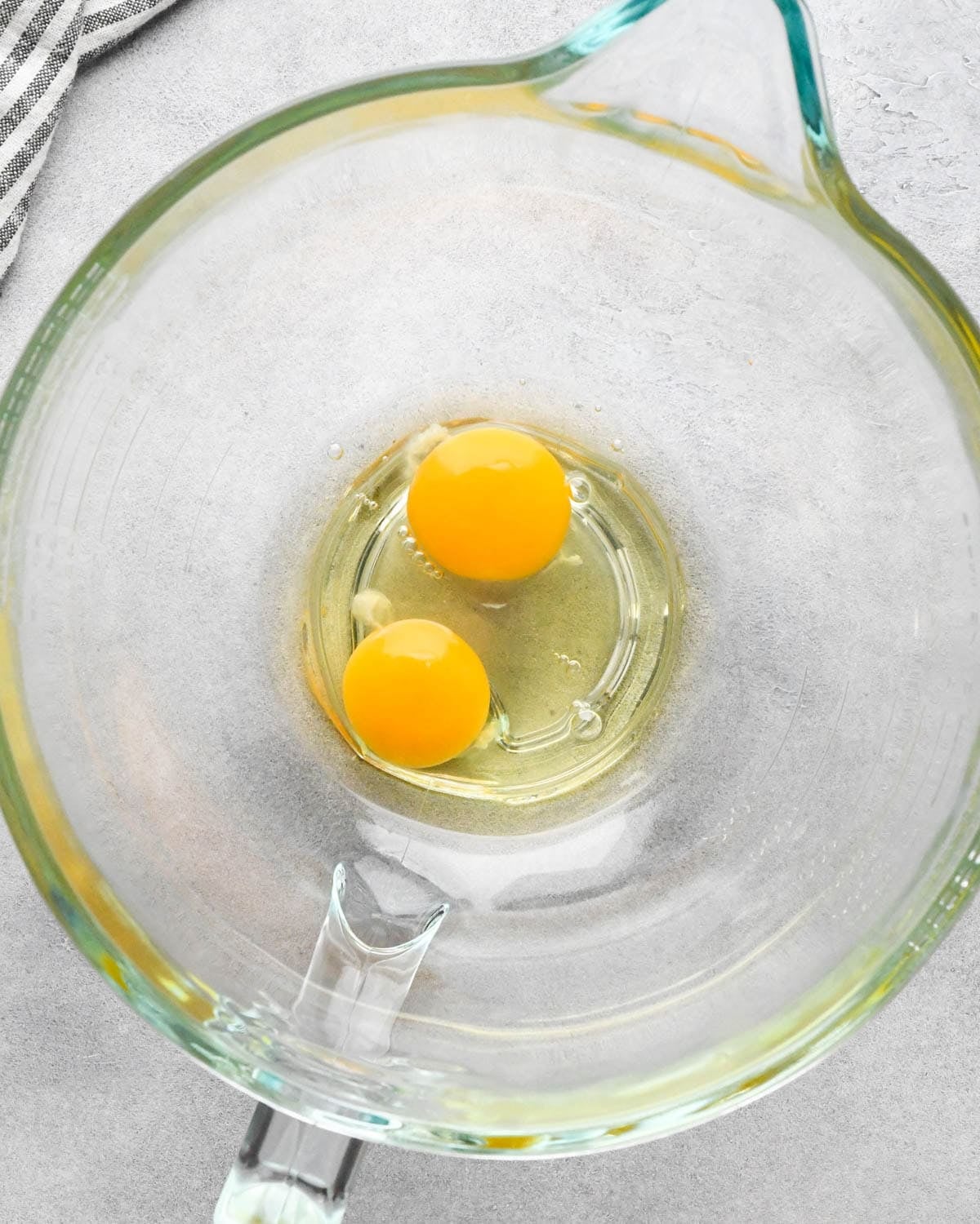 Making buckeye brownies: overhead photo of 2 eggs cracked into a clear measuring bowl.