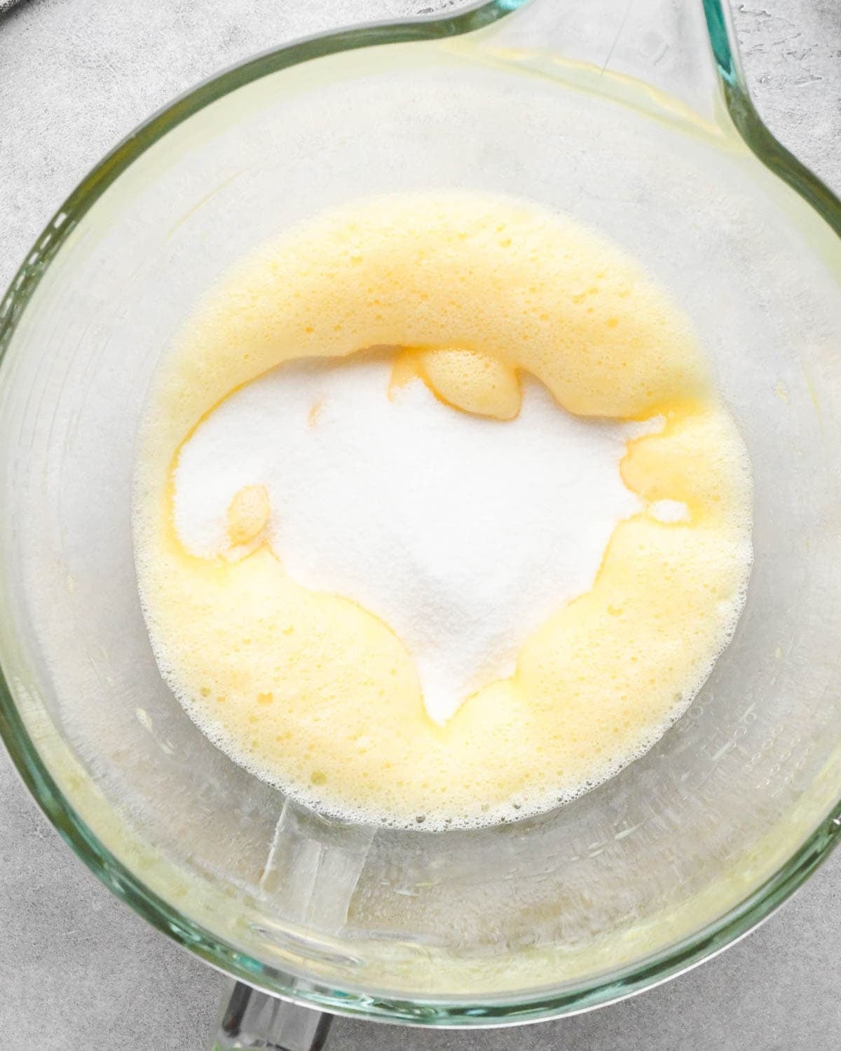 Making buckeye brownies: overhead photo of sugar added to the beaten eggs in a glass measuring bowl.