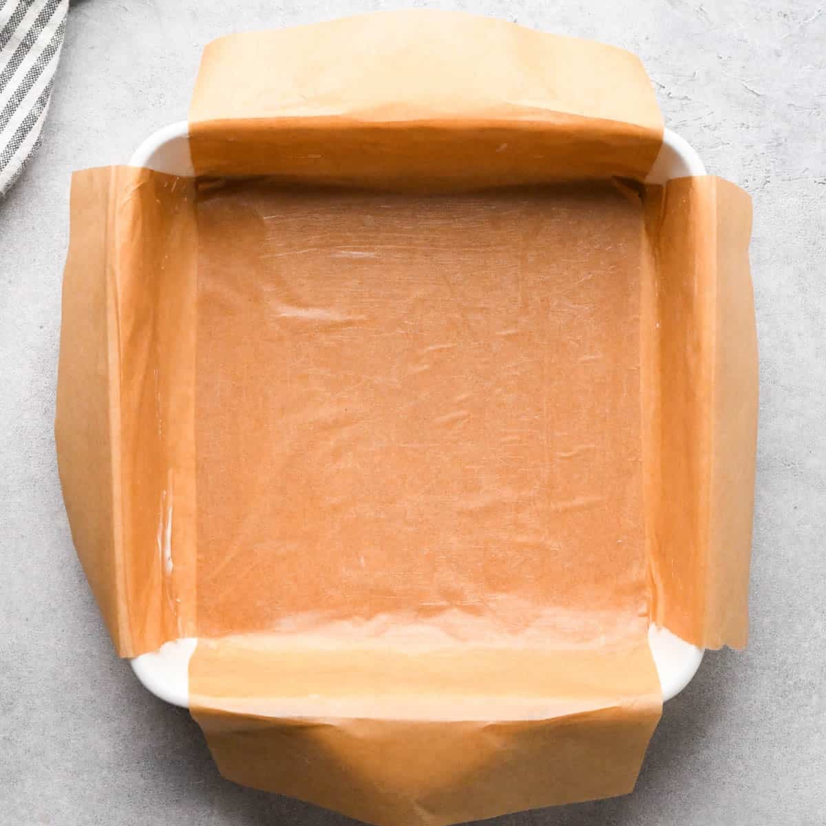 Making buckeye brownies: overhead photo of a 9x9" baking dish lined with lightly greased parchment paper and sitting on a countertop.