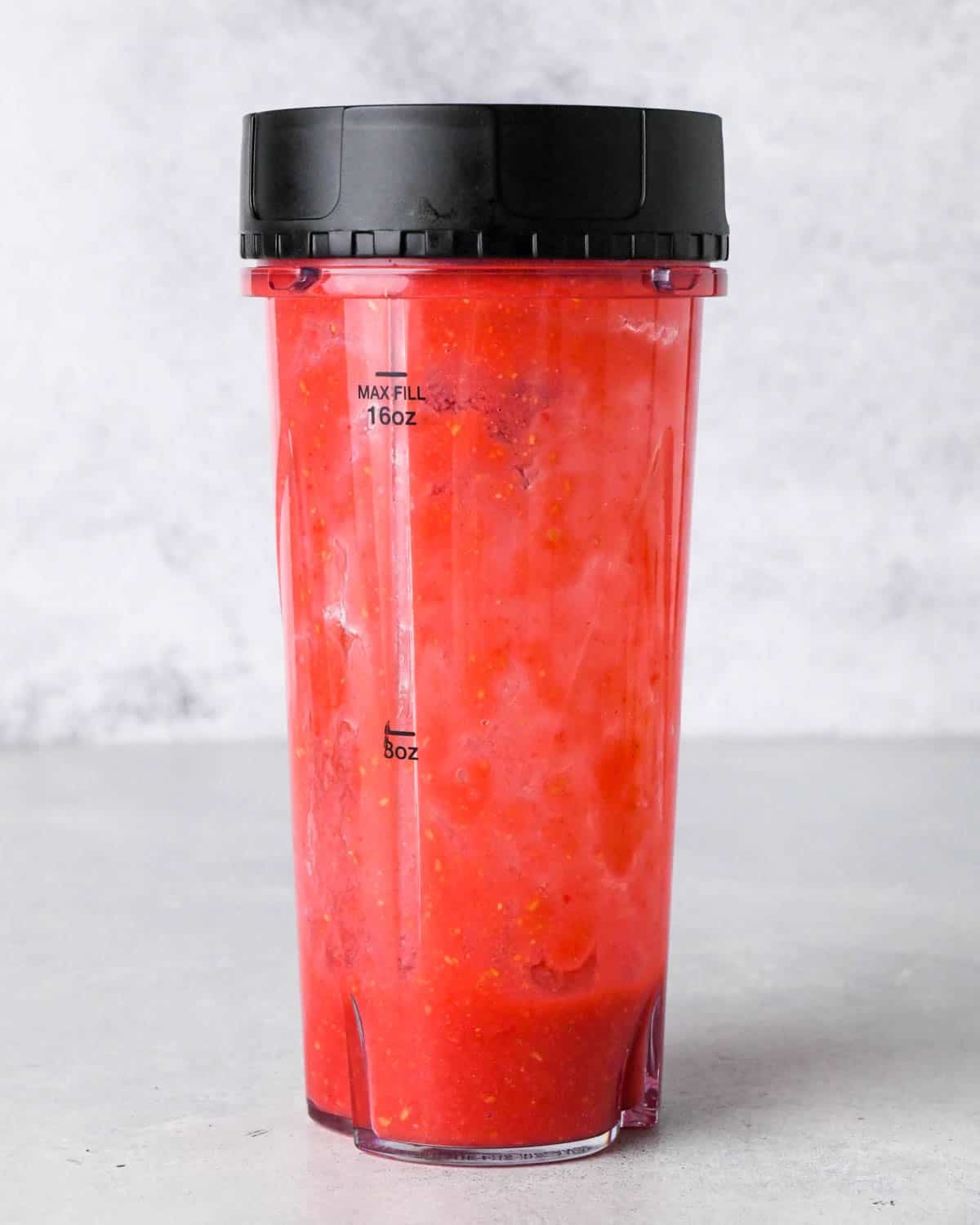 how to make raspberry frosting - raspberries and sugar in a small blending container after blending overhead view front view