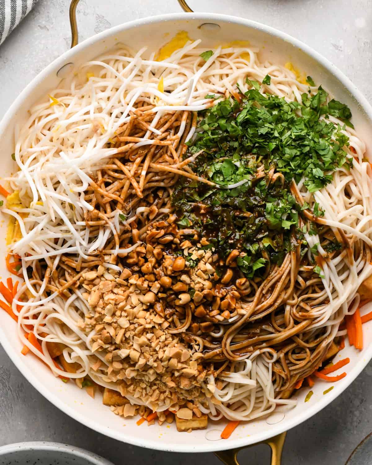 Making Pad Thai: overhead photo of cooked noodles, bean sprouts, cilantro and sauce added in with the tofu and vegetable mixture in a skillet.