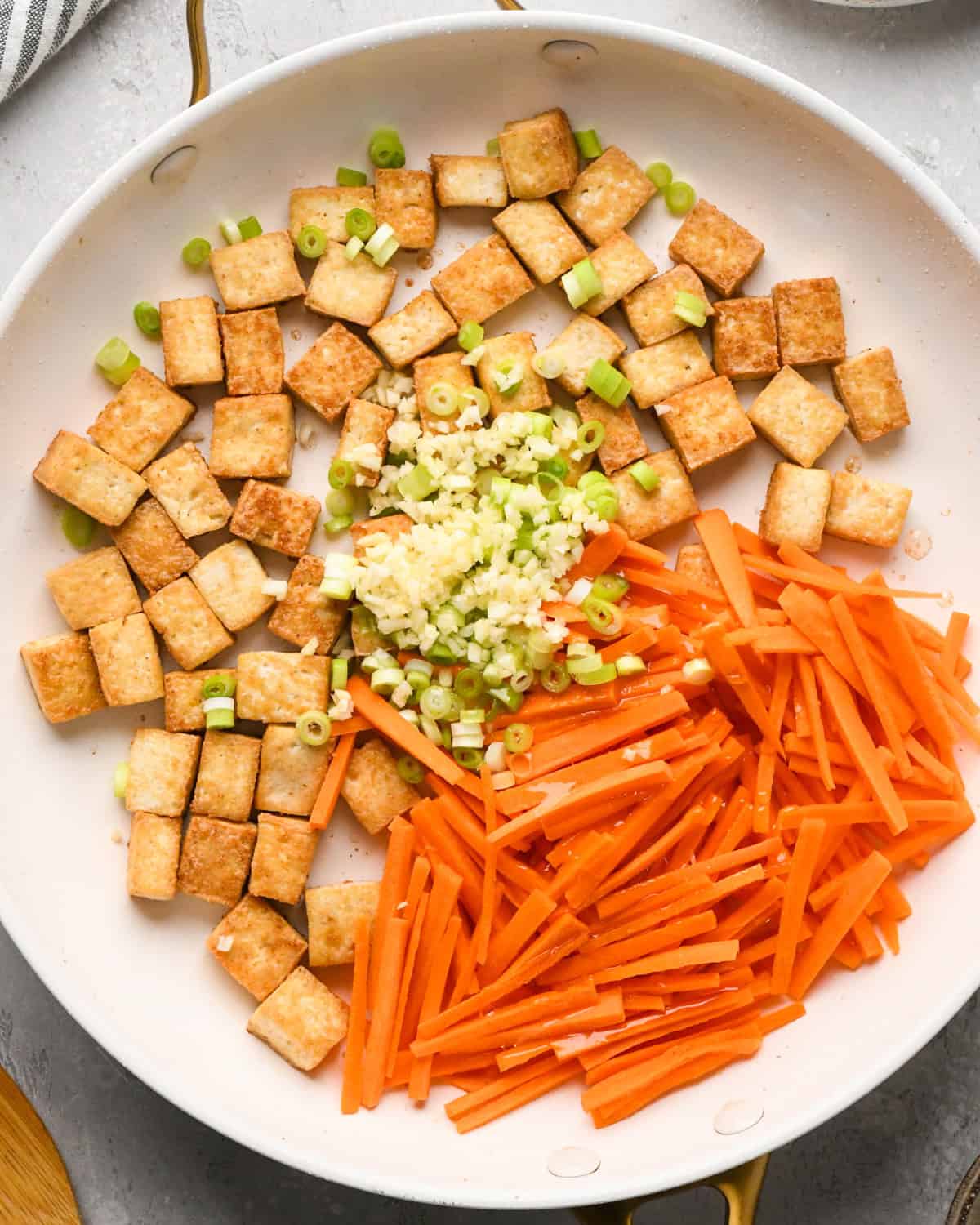 Making Pad Thai: overhead photo of carrots, onion, garlic and oil added to a skillet with cooked tofu.