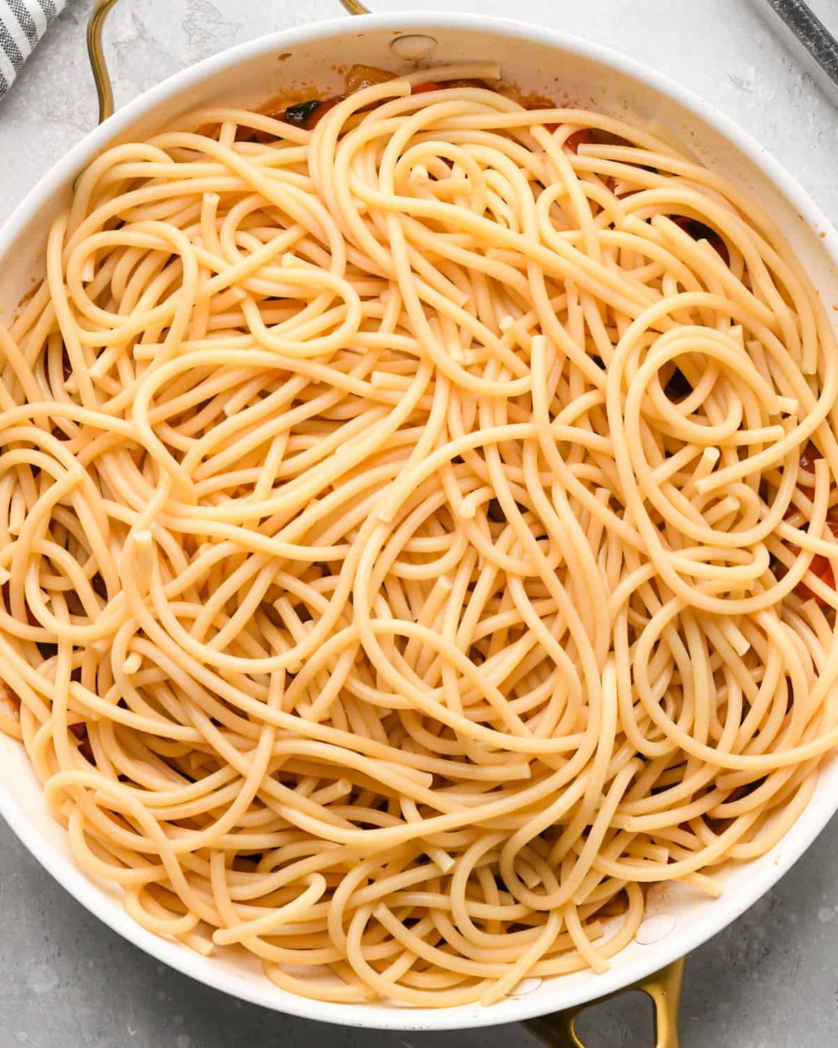 Making pasta with burrata cheese: overhead photo of cooked pasta being added to the sautéed vegetables in a skillet.