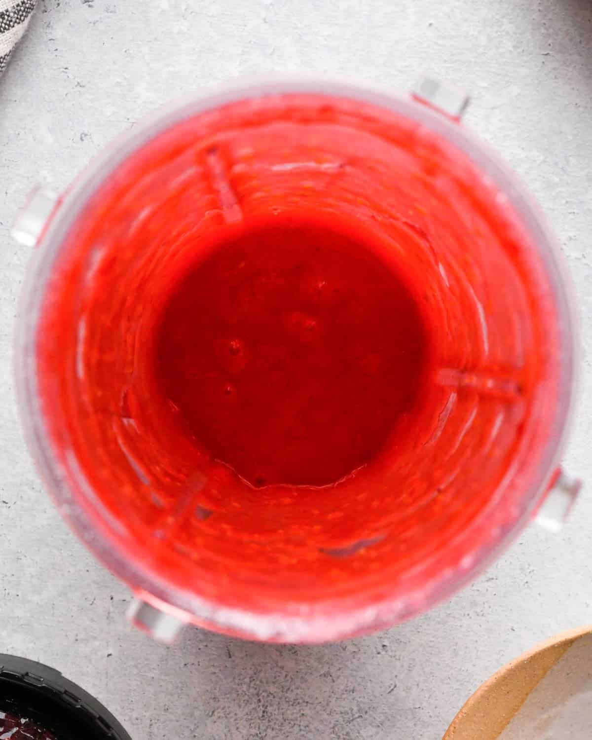 how to make raspberry frosting - raspberries and sugar in a small blending container after blending overhead view