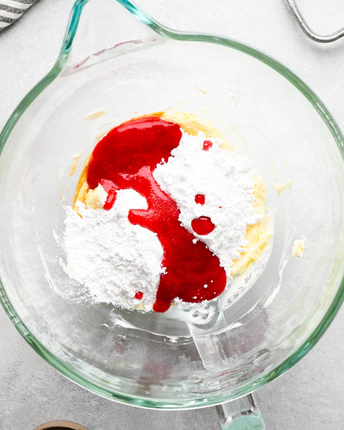 how to make raspberry frosting - raspberry puree and powdered sugar added to the beaten butter in a glass mixing bowl before mixing