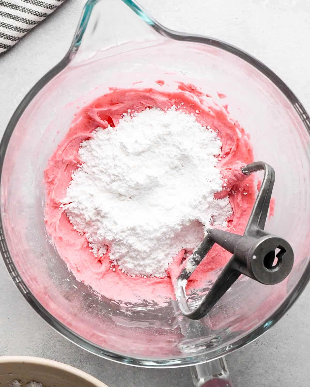 how to make raspberry frosting - powdered sugar added to the mixture in a glass bowl with the paddle attachment also in the bowl