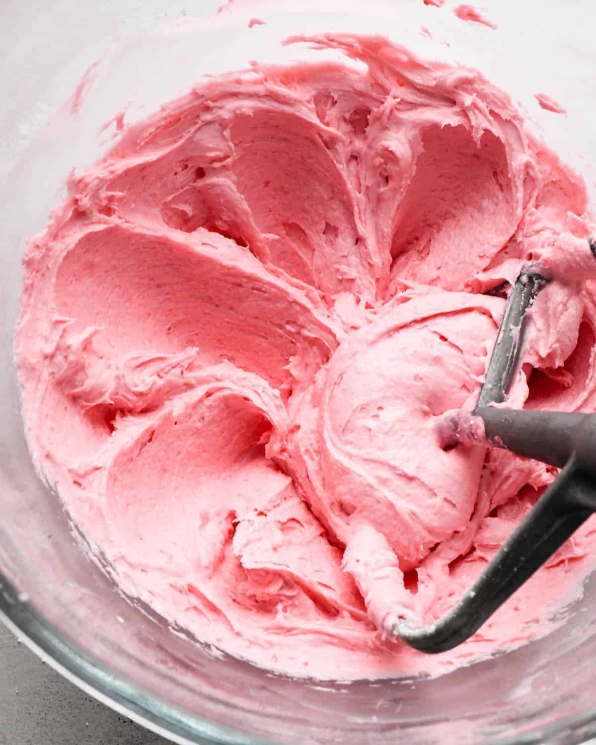 raspberry frosting in a glass mixing bowl - the paddle attachment is also in the mixing bowl