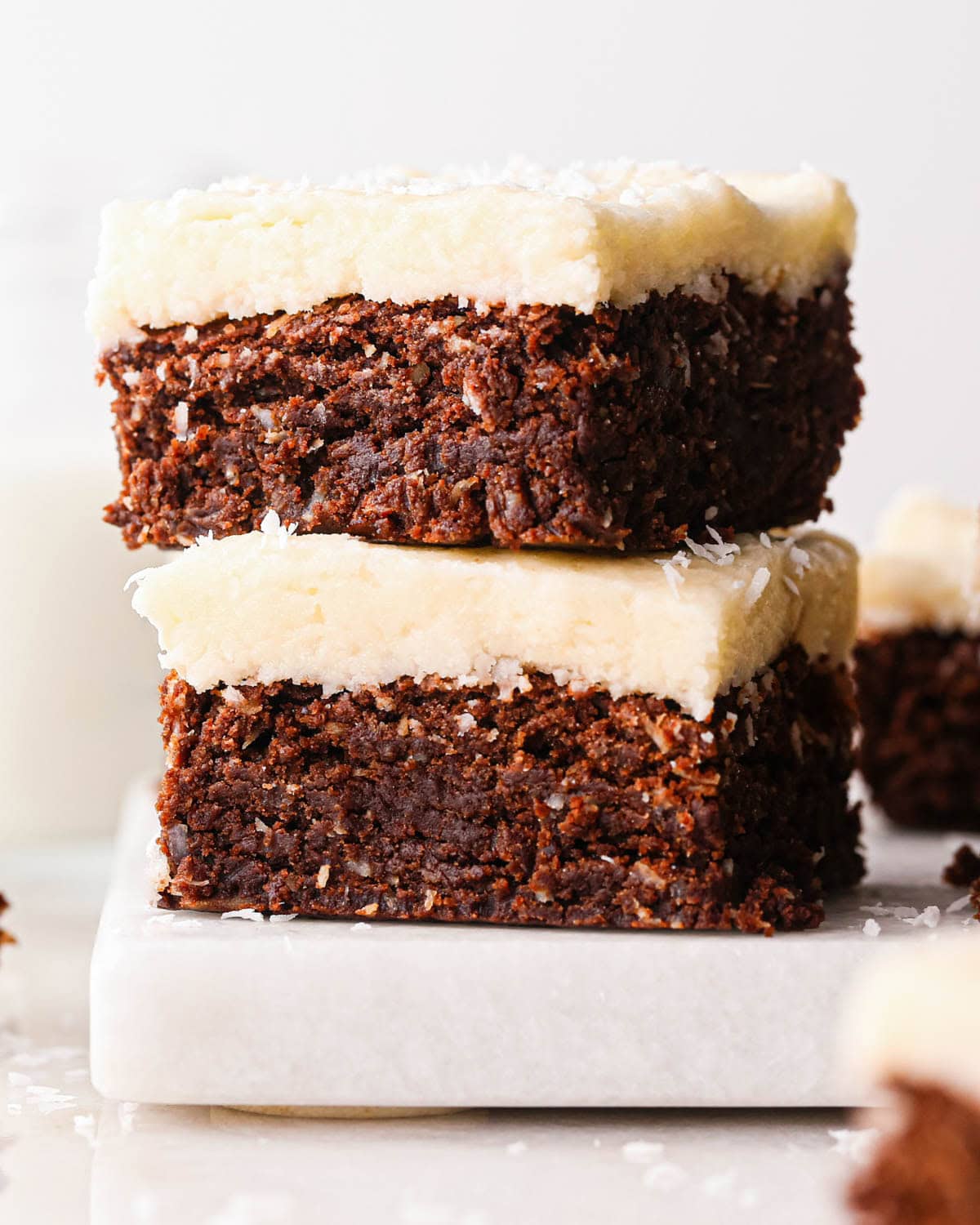 a stack of two chocolate coconut brownies with more brownies in the background