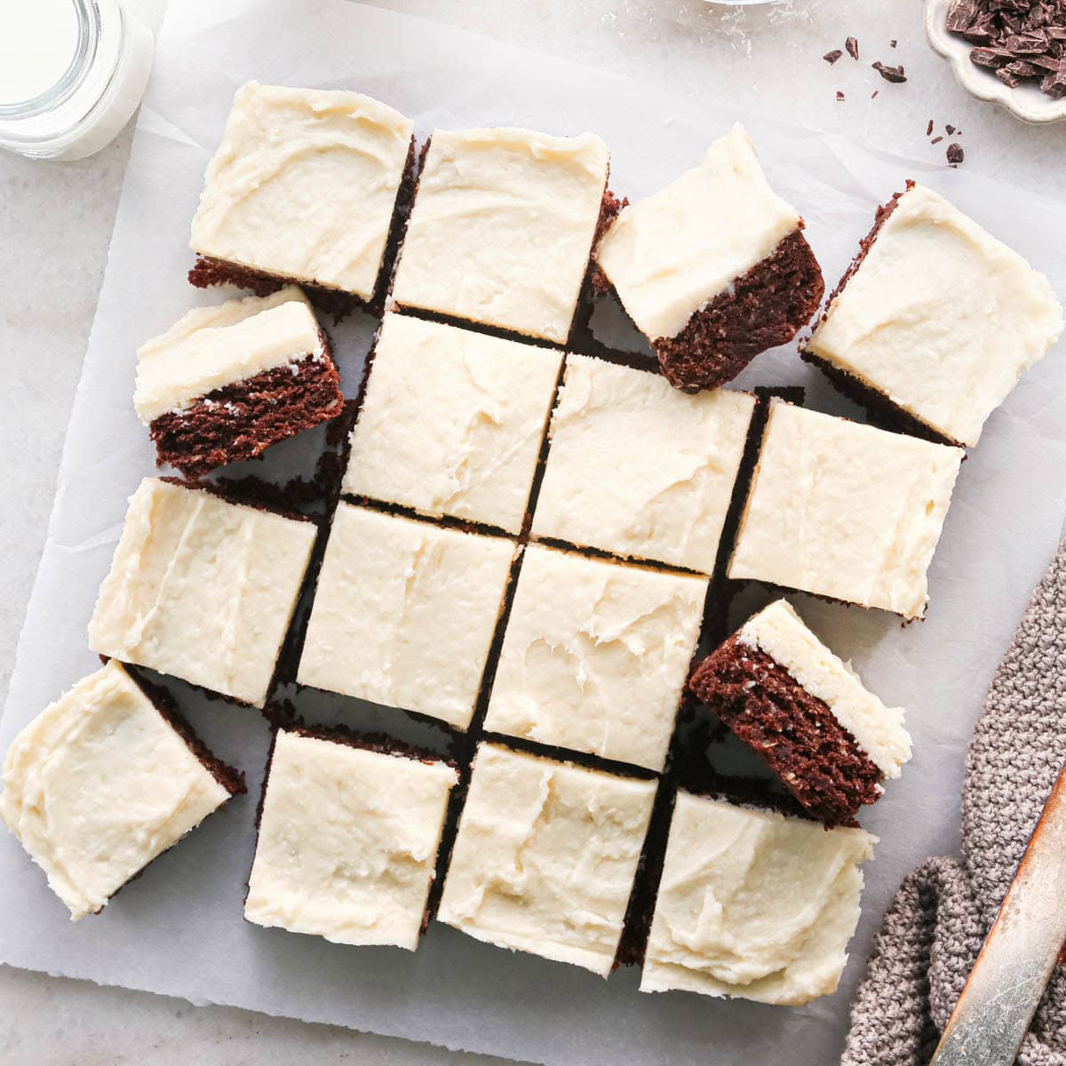 chocolate coconut brownies with coconut frosting cut into 16 squares on a piece of white parchment paper